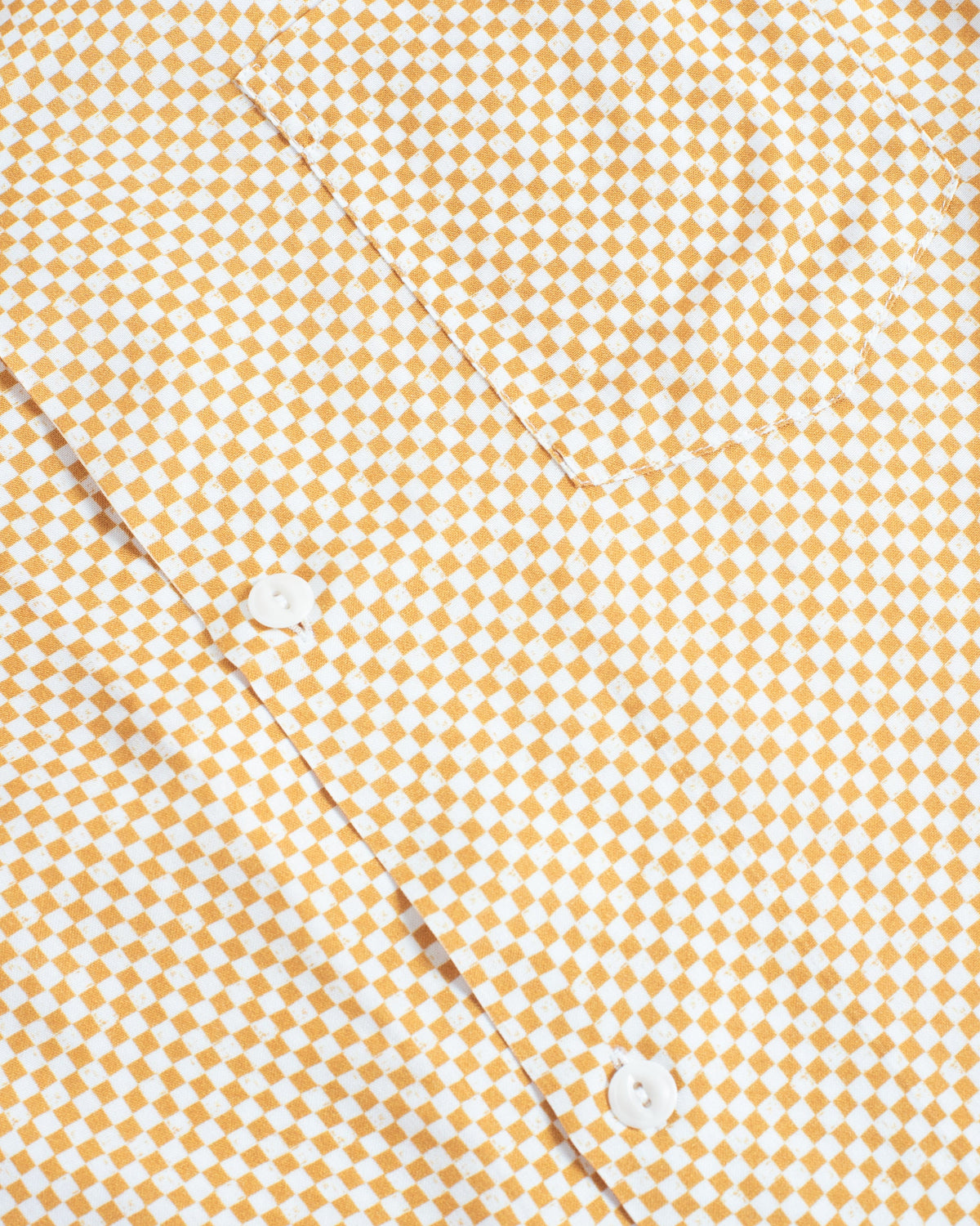 Close-up of a yellow and white checkered patterned shirt with white buttons.