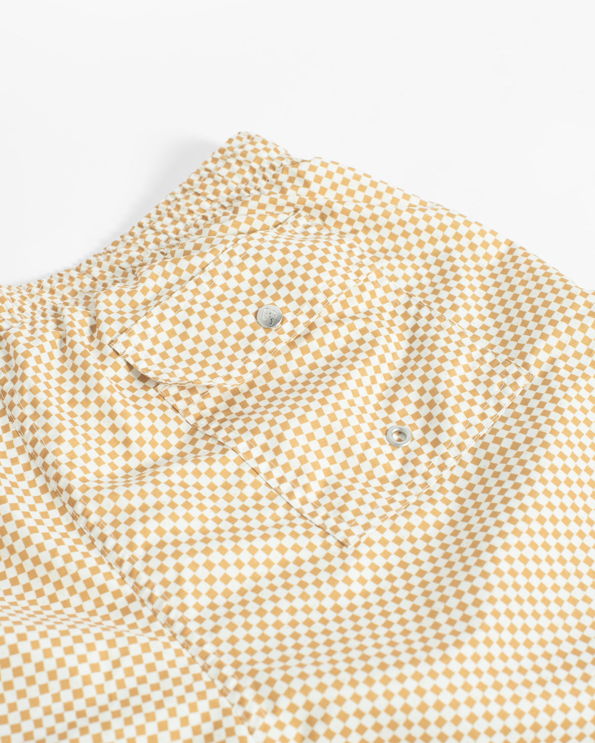 Close-up of a yellow and white checkered shirt with a button-down collar and silver buttons, laid flat on a white background.