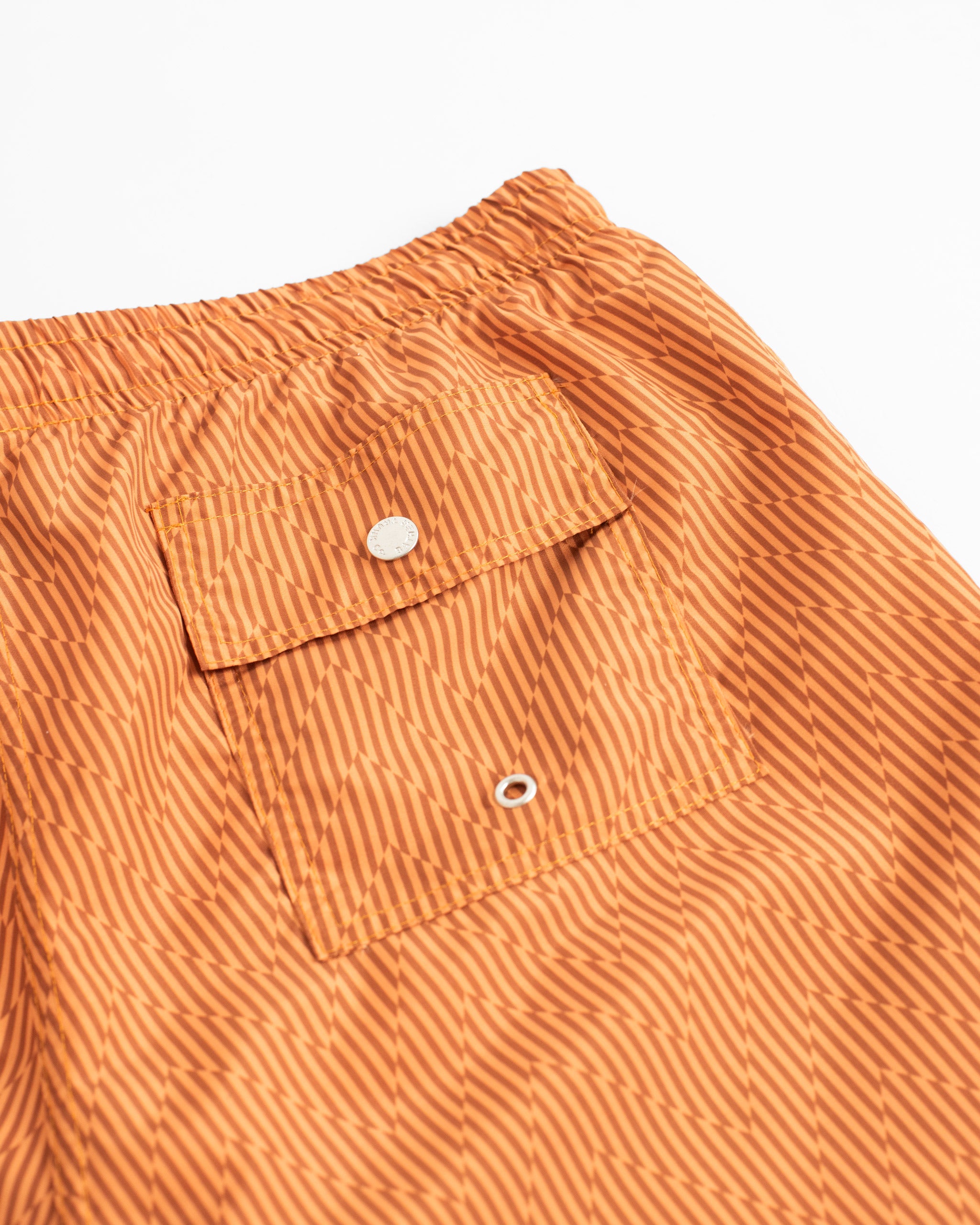 Close-up of Bather orange zigzag pattern swim trunks with a back button-closure pocket