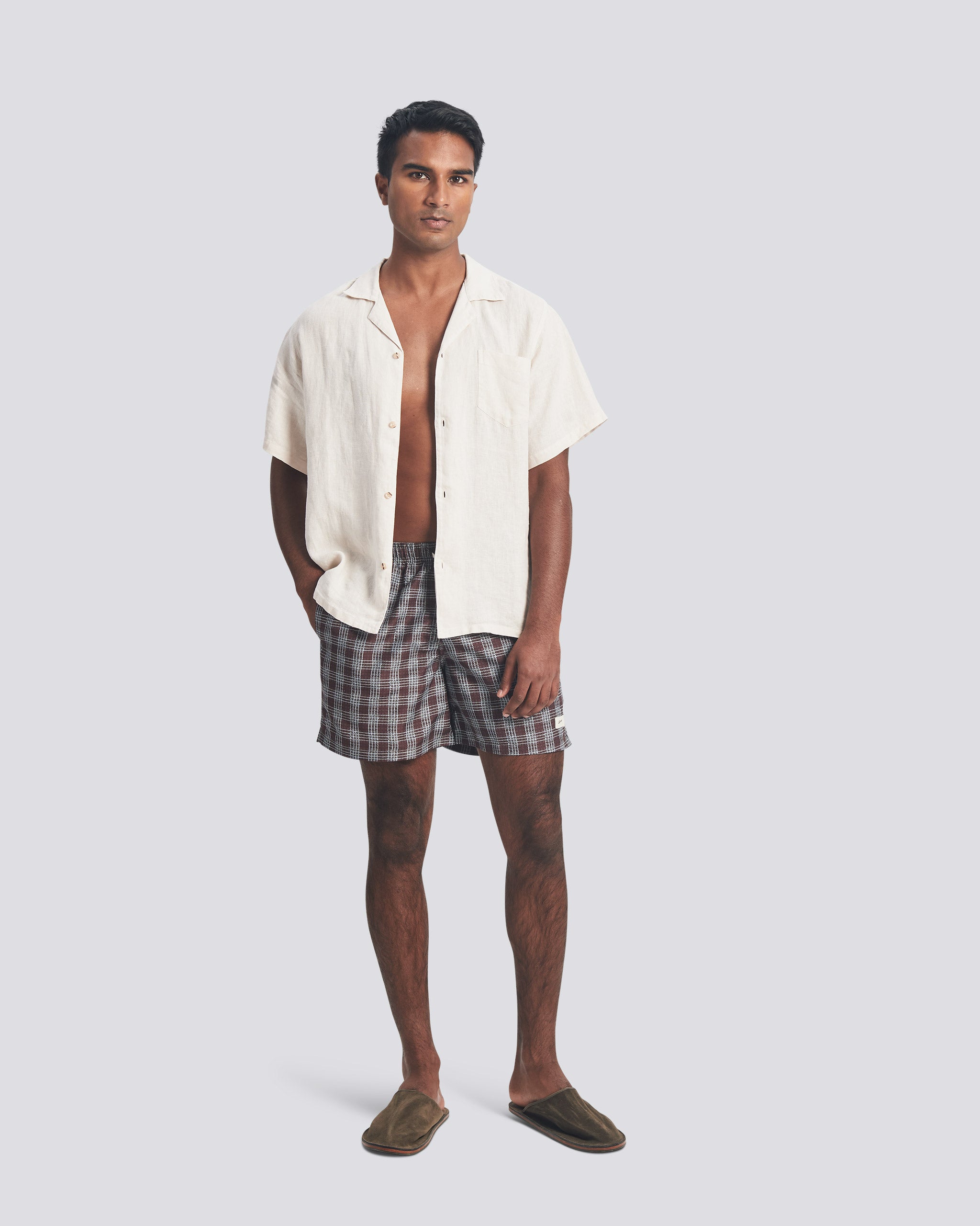 Male model wearing Bather plaid swim trunks with a Bather white camp shirt