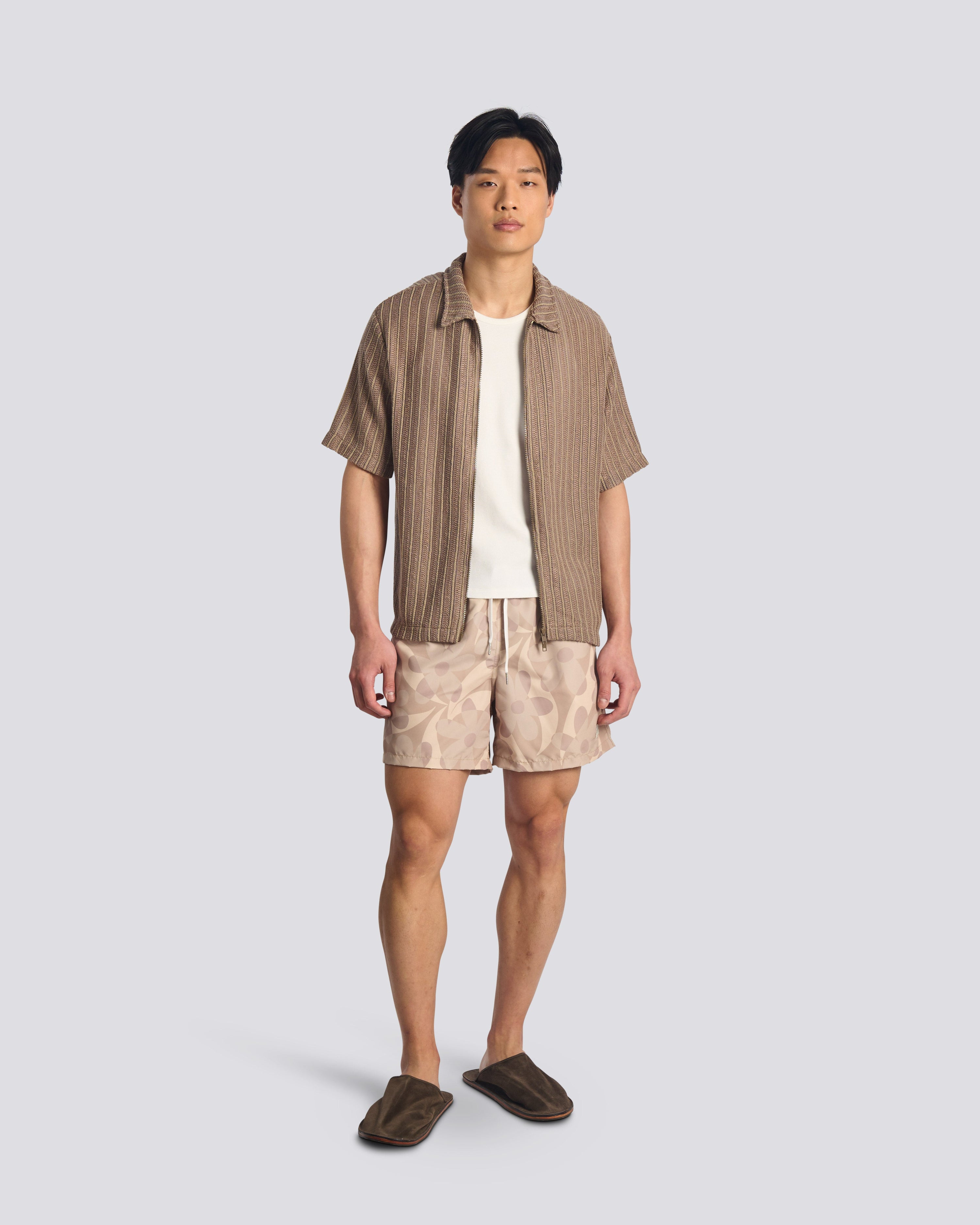 Man wearing Bather beige floral swim trunks with Bather brown short sleeve shirt