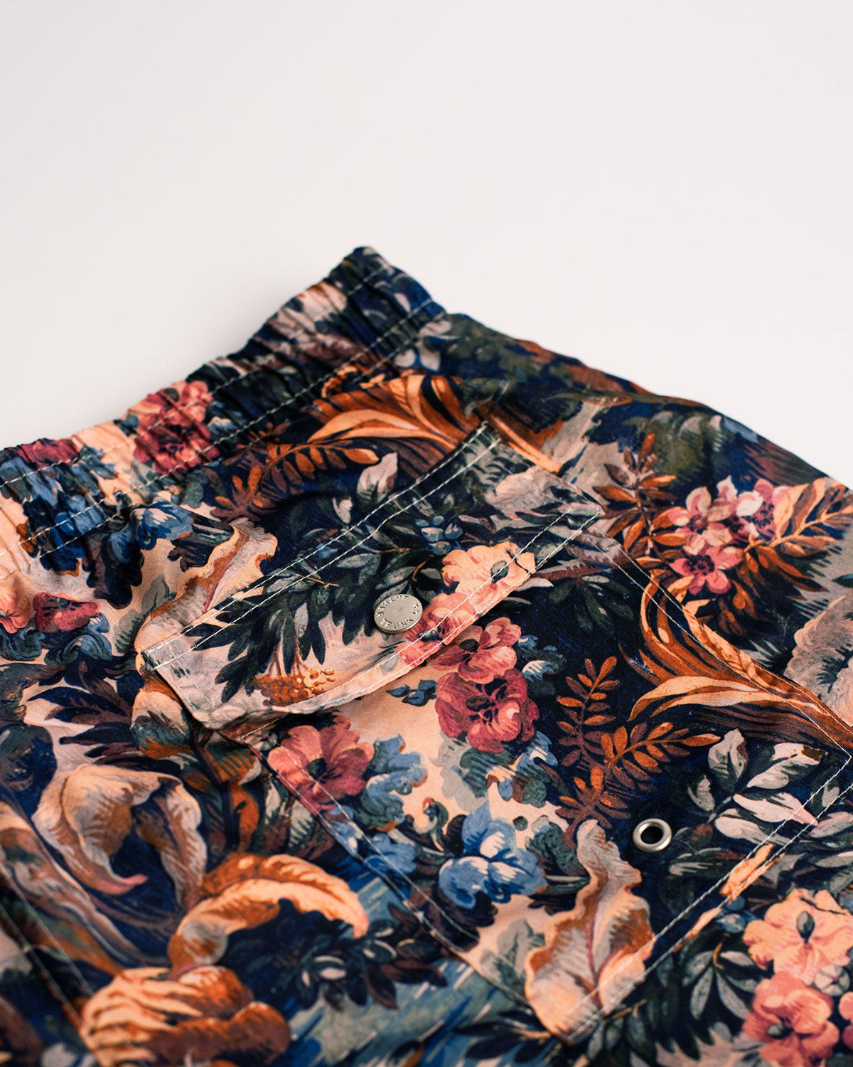 Close up of mens blue botanical forest swim trunks with button closure back pocket