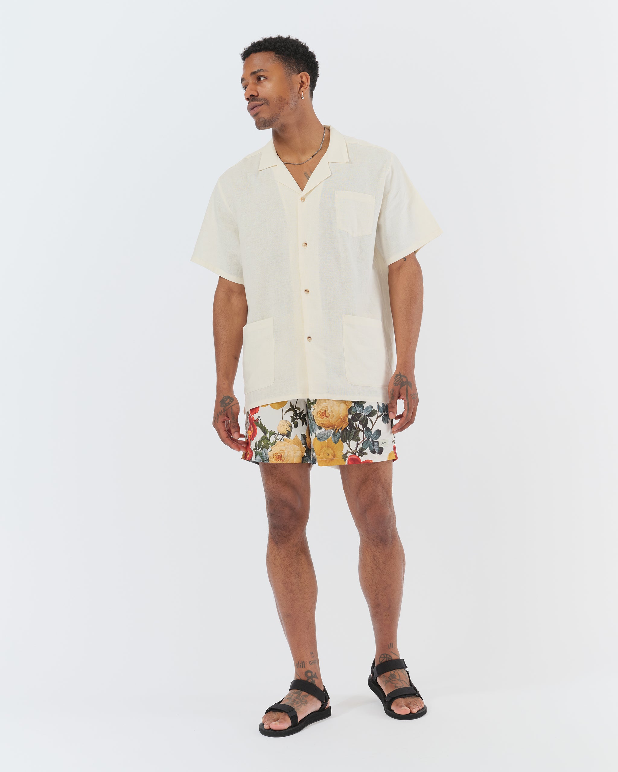 Male model wearing Bather ivory swim trunks with a vintage floral print, and Bather white camp shirt 