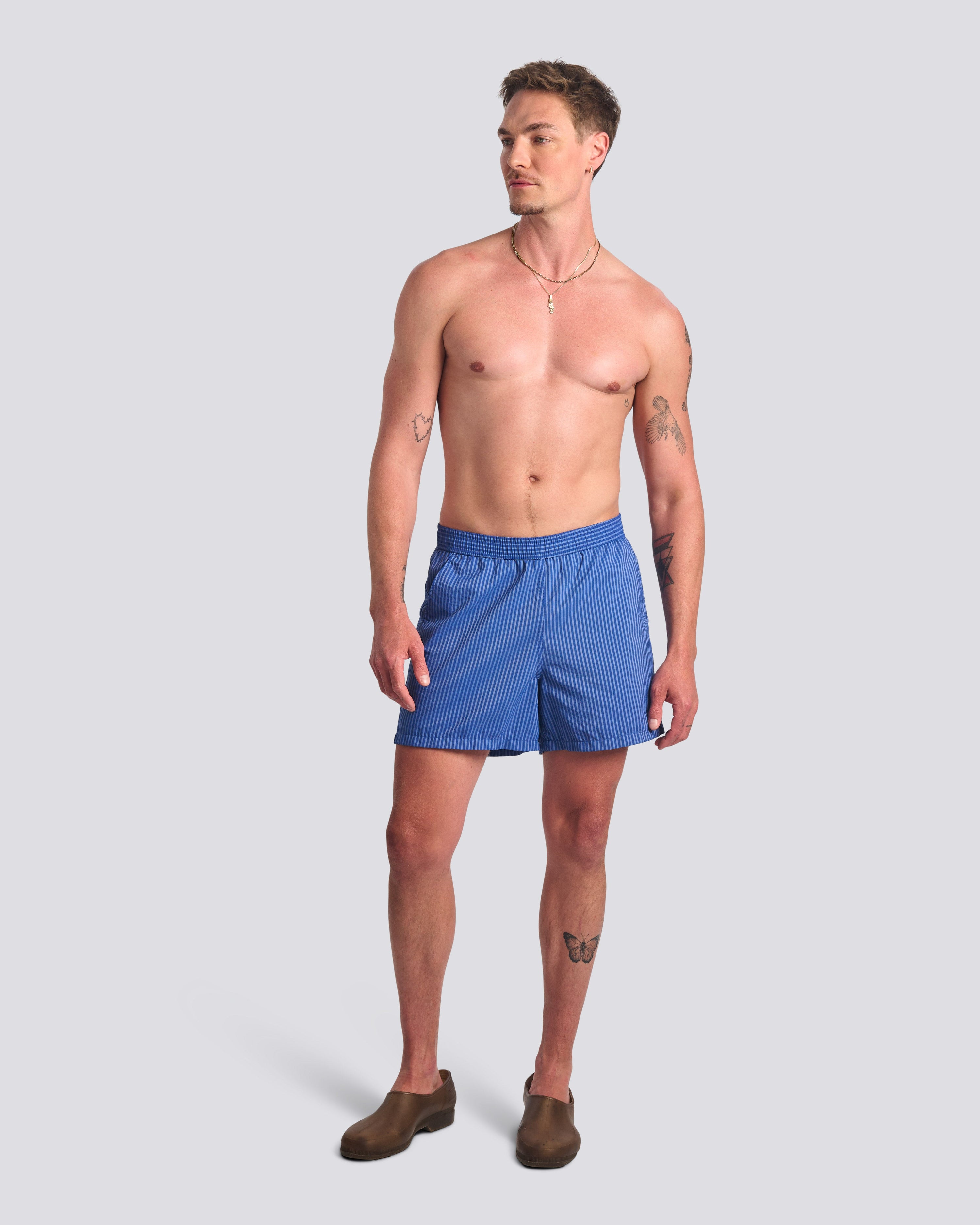 Man wearing blue pinstripe swim trunks with hidden elastic waistband