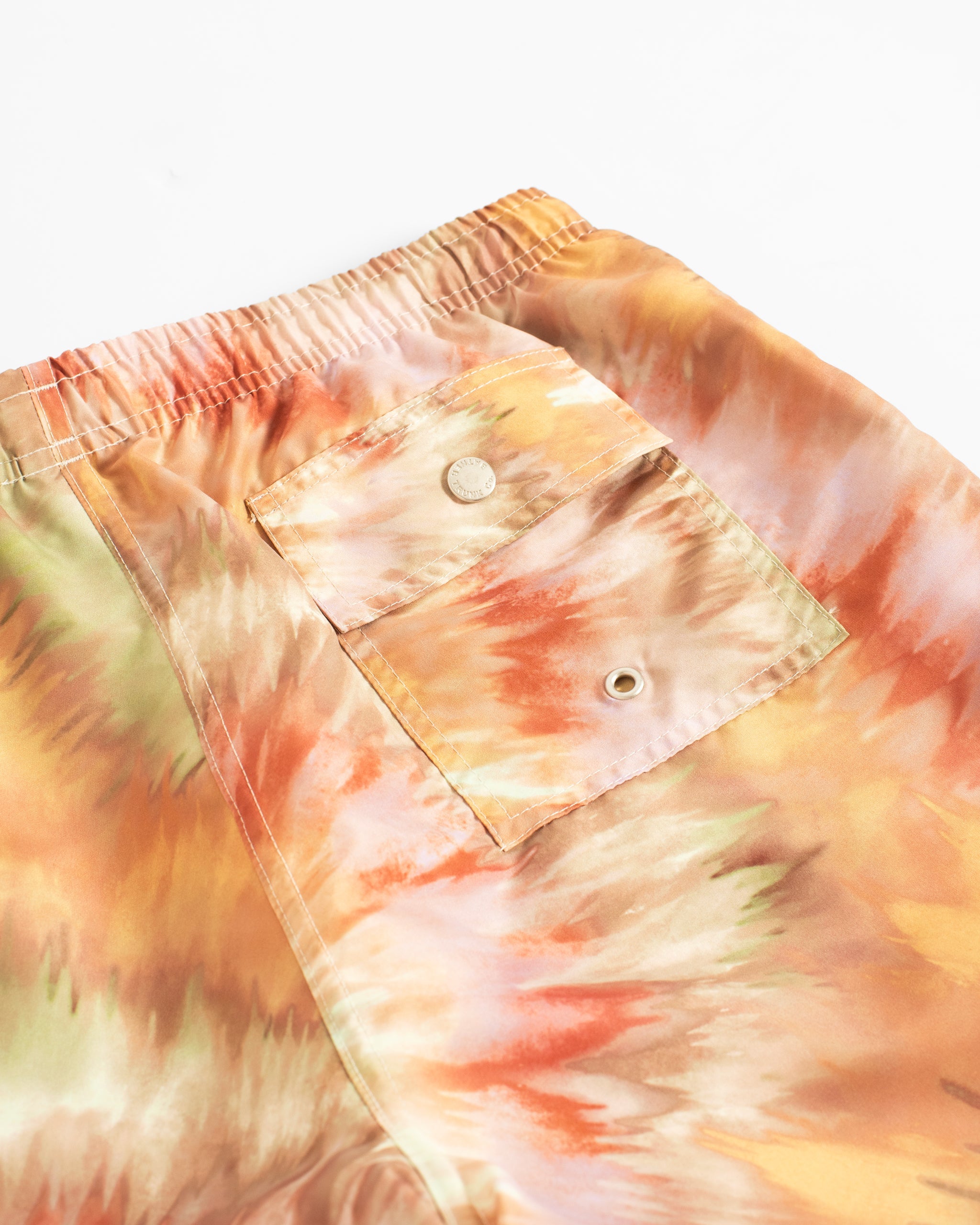 Close-up of men’s abstract tie-dye swim trunks with button closure back pocket