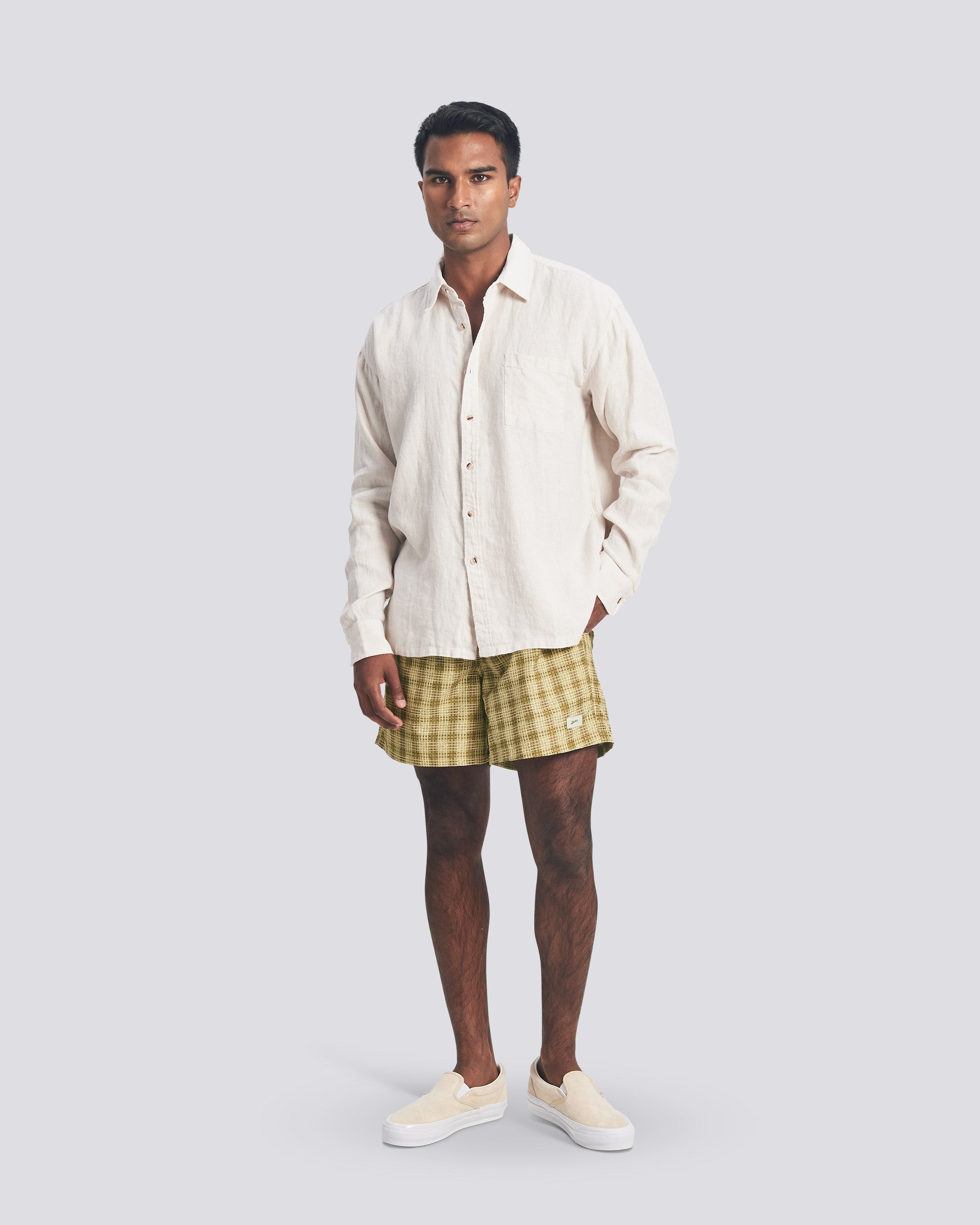 Model wearing men’s yellow plaid patterned swim trunks with Bather cream button up leisure shirt 