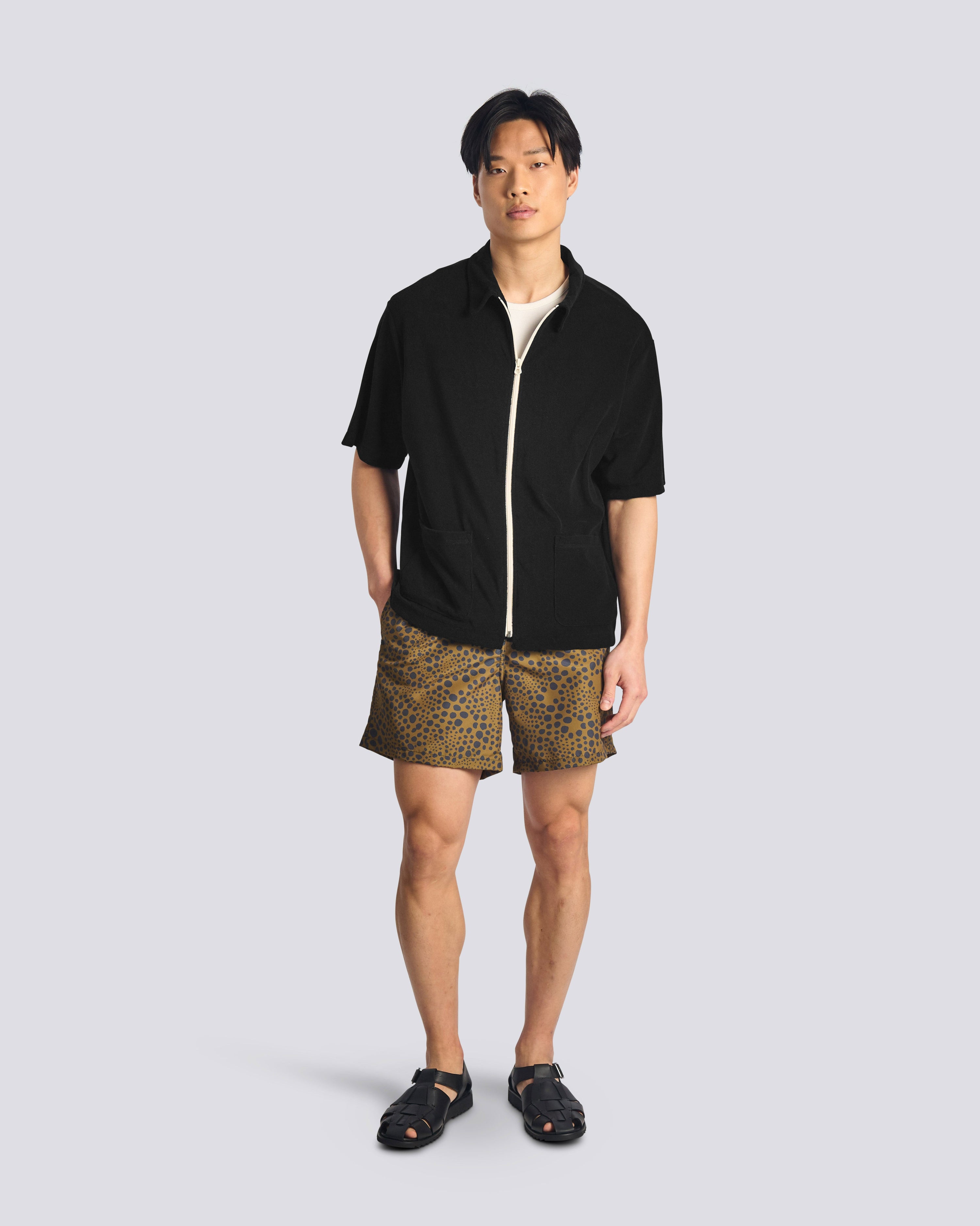 Man wearing Bather army green spotted swim trunks with Bather navy short sleeve shirt