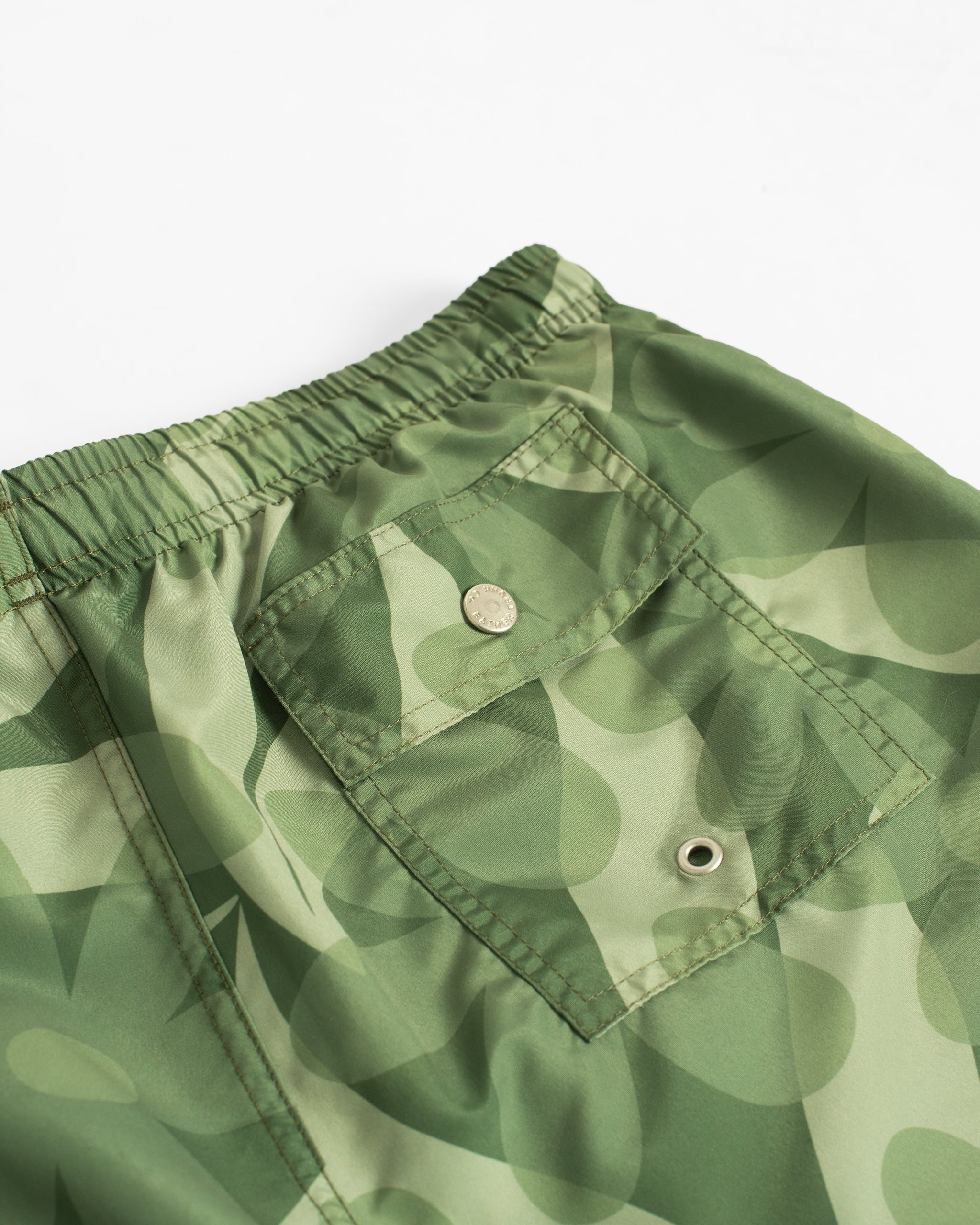 Close-up of men’s green floral swim trunks back pocket with button closure