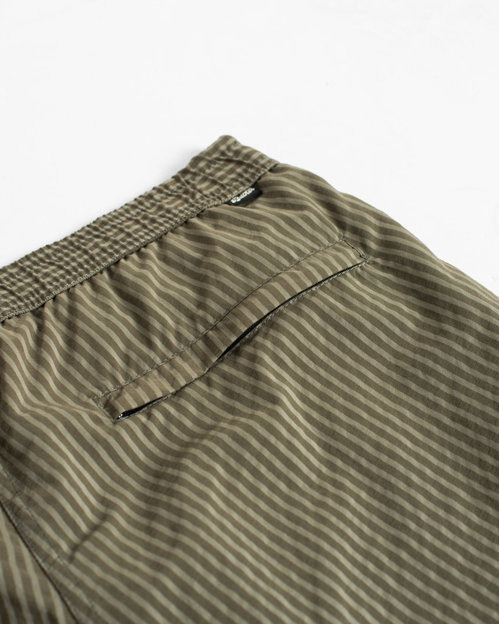 Close-up of men’s army green pinstripe swim trunk with hidden zipper closure pocket