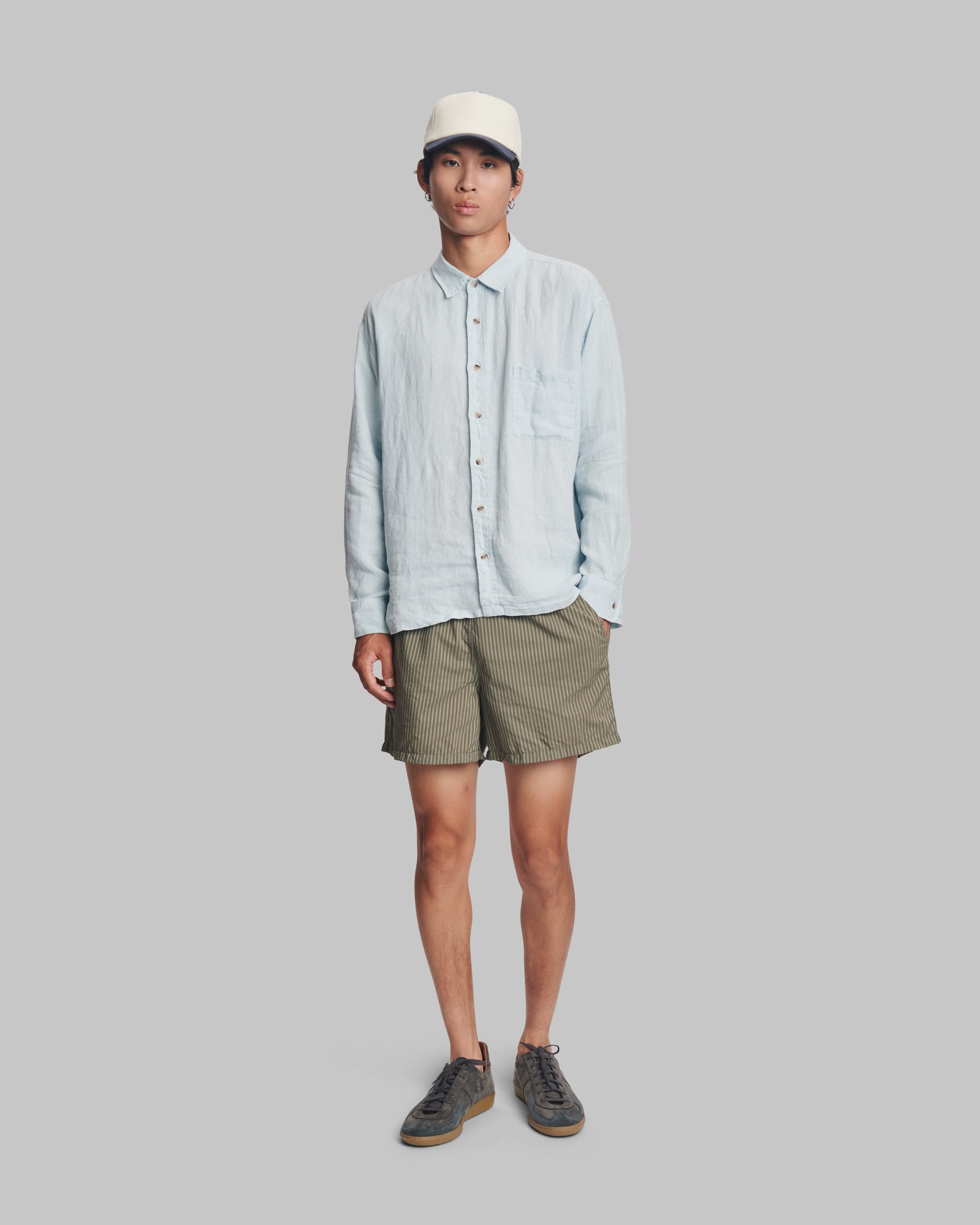 Man wearing men's army green pinstripe swim trunks with hidden elastic waistband