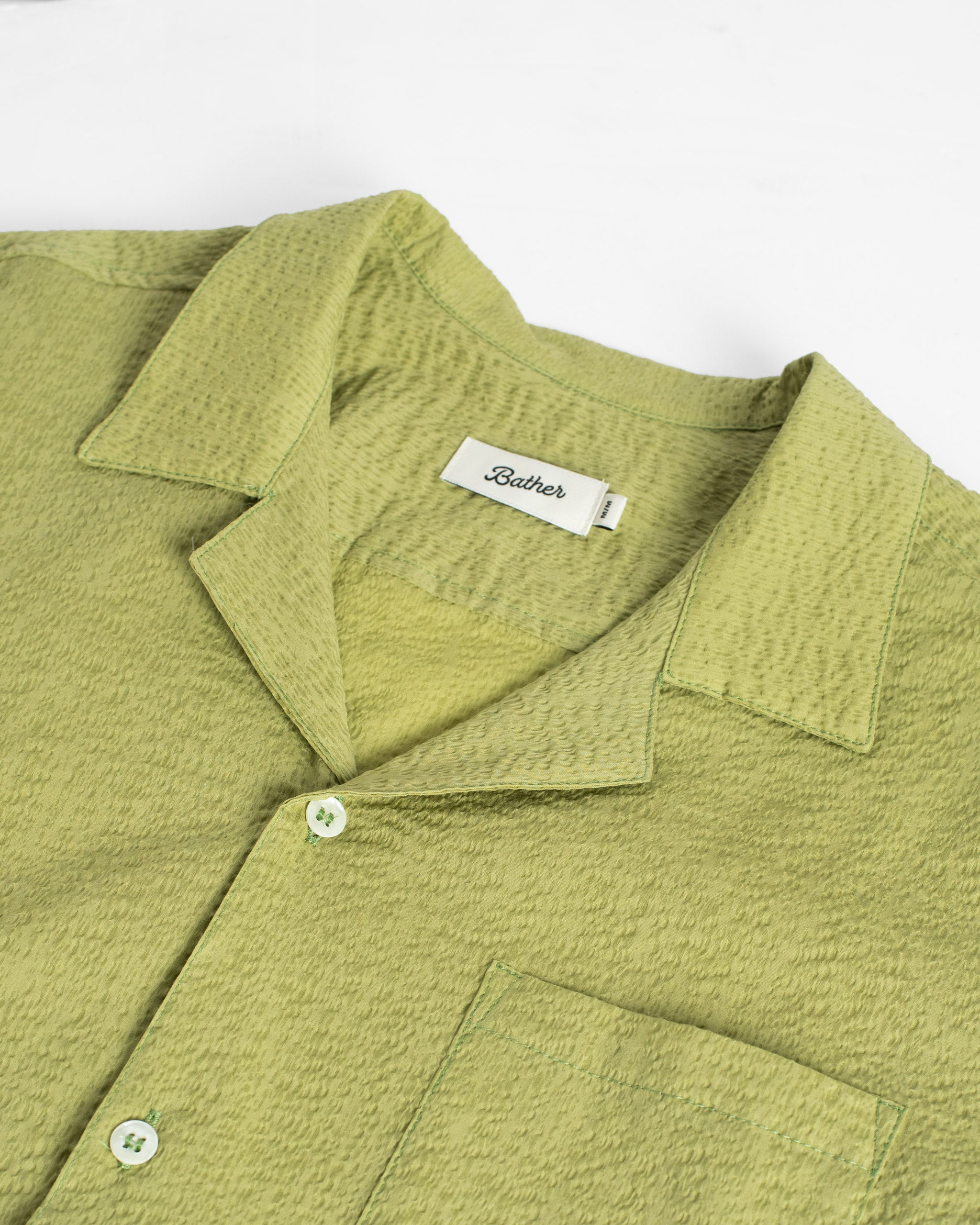 Green textured shirt with a brand label on a white background