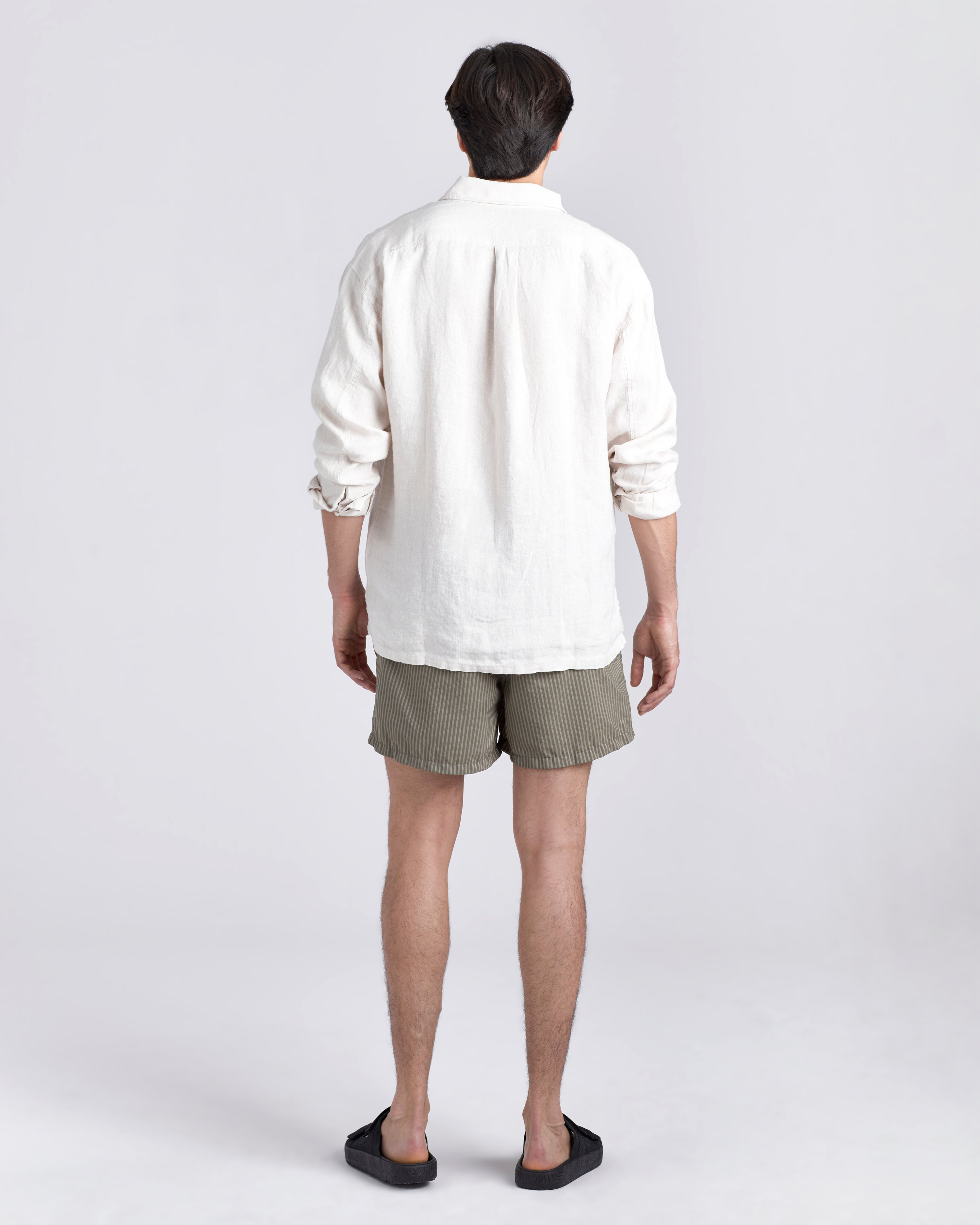 Back of male model in white Bather leisure shirt wearing a green swim trunk with a subtle stripe featuring an elastic drawstring waistband on white background