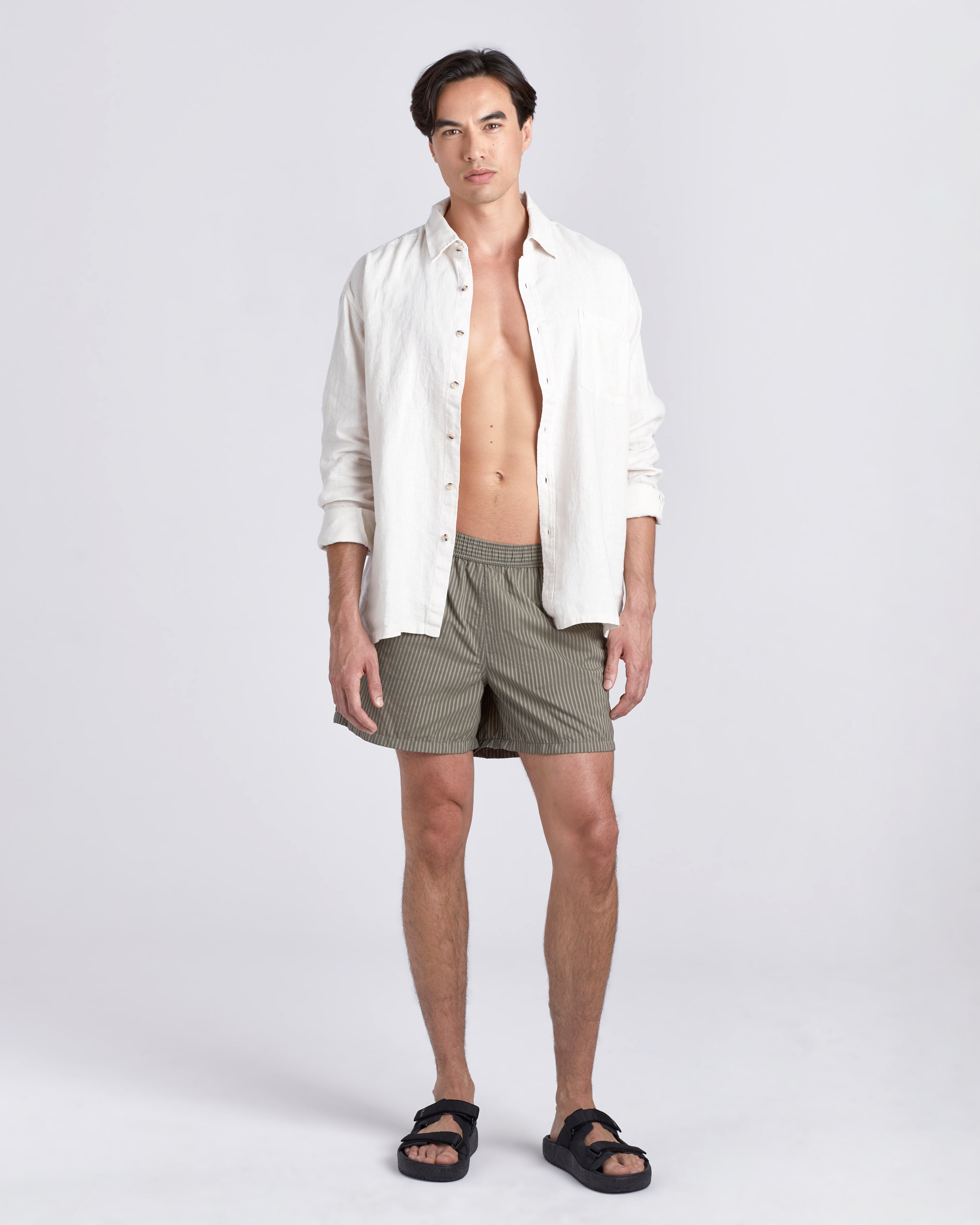 Male model in white Bather leisure shirt wearing green swim trunk with a subtle stripe featuring an elastic drawstring waistband on white background