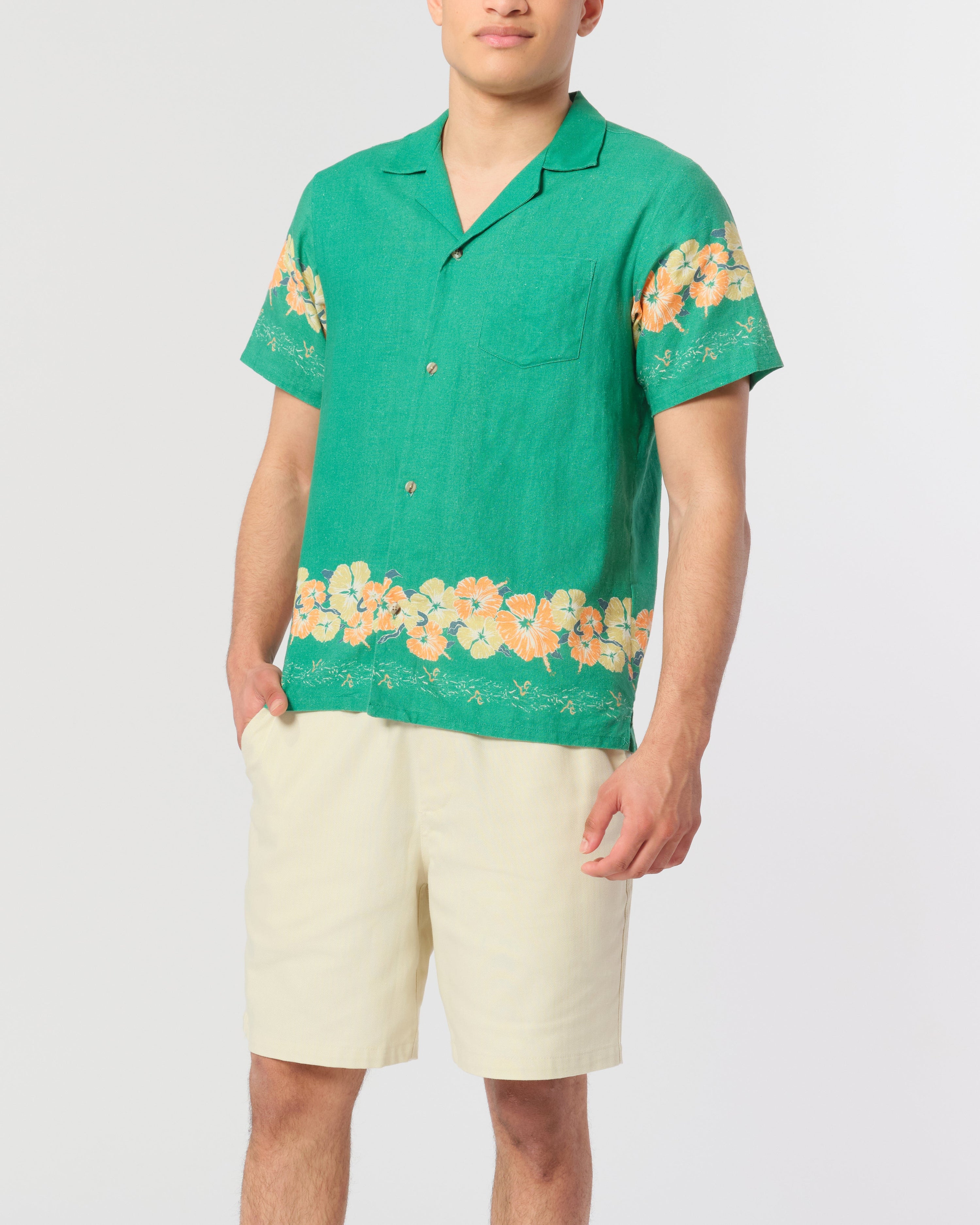 model wearing Green camp shirt with floral motif pattern on the sleeves and bottom hem