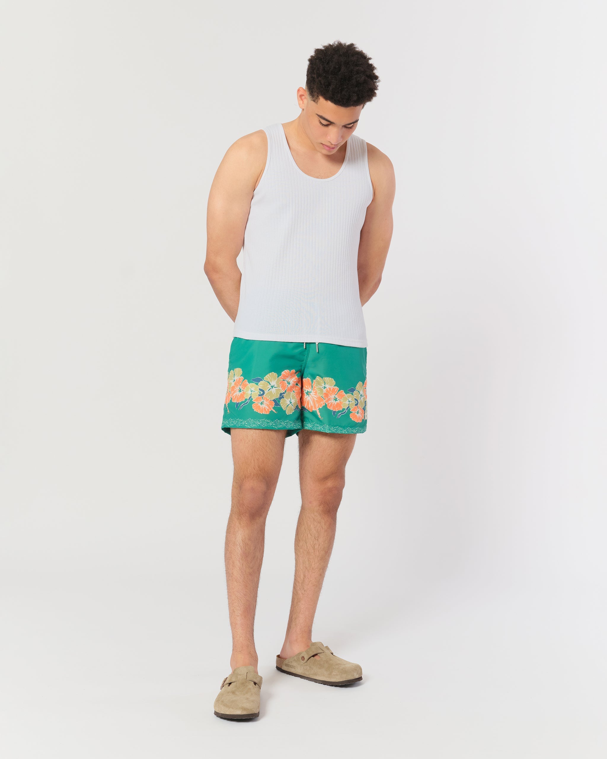 model wearing Green swim trunk with floral motif pattern on the bottom of the leg