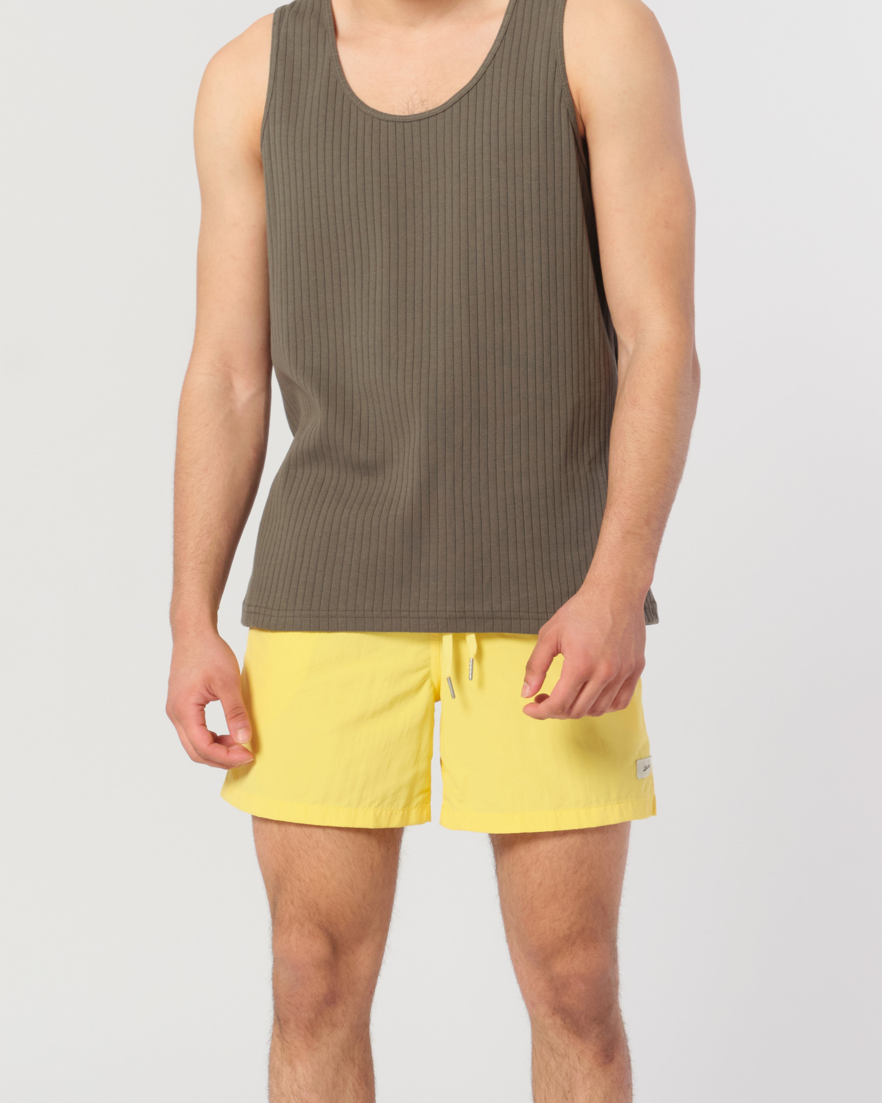 model wearing A solid yellow swim trunk in canary yellow with a matching drawstring