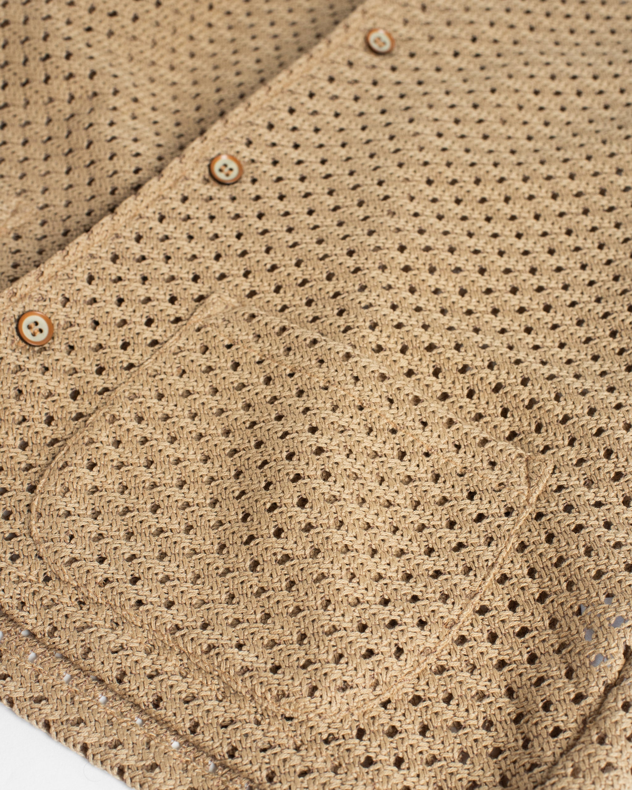 A close-up detail of the Bather Men's Beach Mesh Traveler Shirt, showcasing the intricate natural-colored Japanese cotton crocheted mesh fabric, a front patch pocket, and tonal buttons.