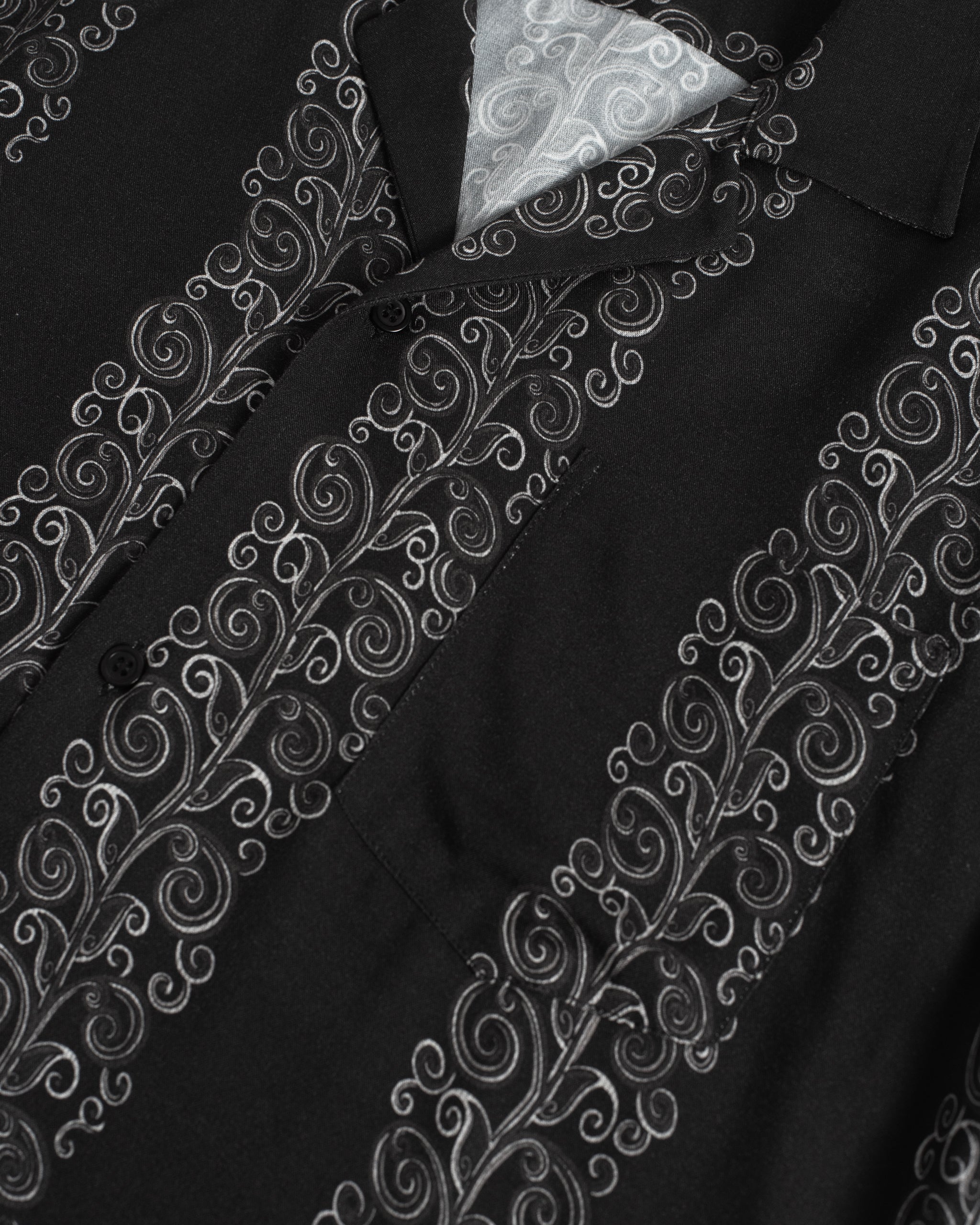 A close-up detail of the Bather Men's Black Fiesta Camp Shirt, showcasing the lightweight black rayon fabric with a subtle vertical "Fiesta" stripe pattern and tonal black buttons.