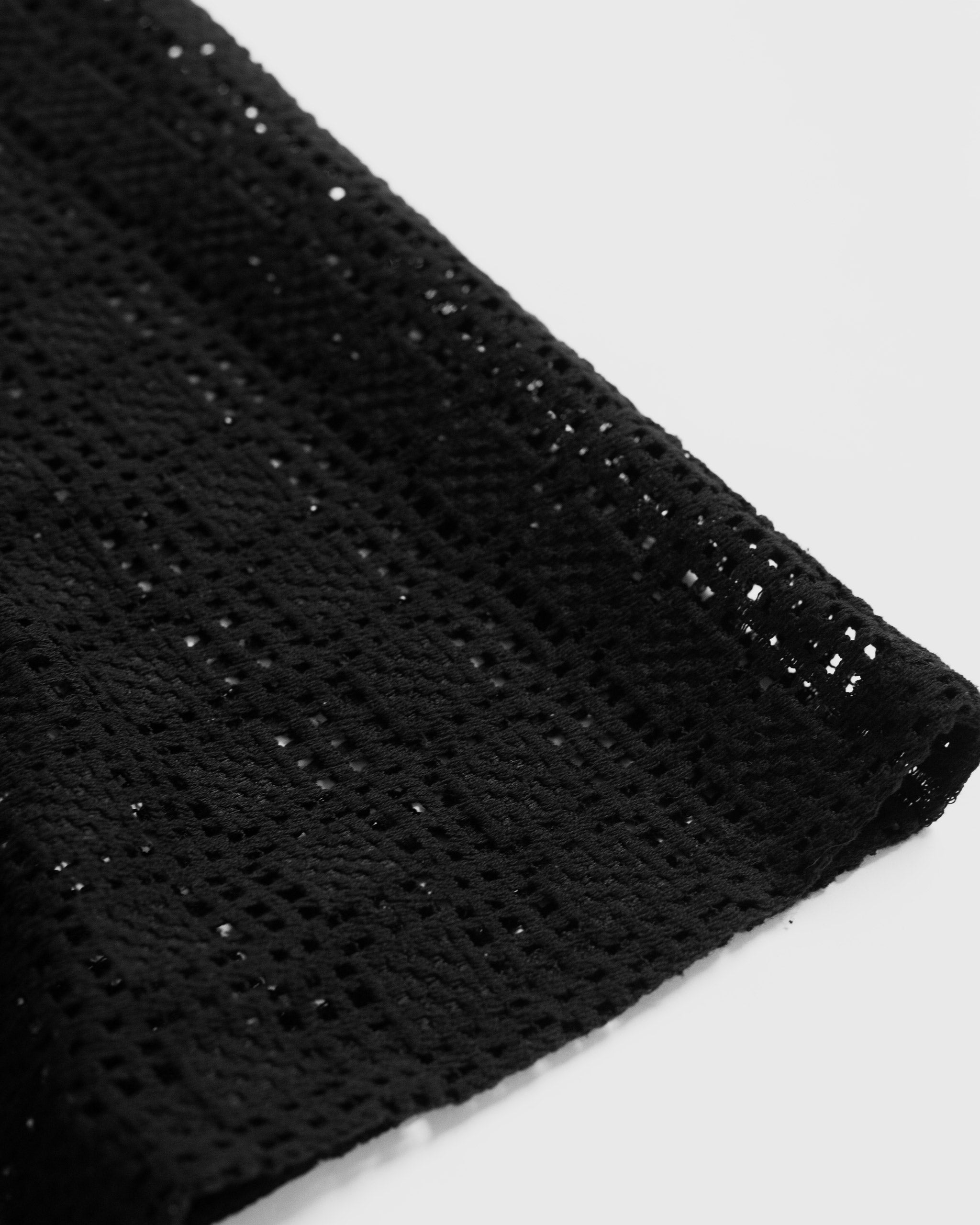 A close-up detail of the Bather Men's Black Lattice Tank Top, showcasing the intricate texture of the black open-knit lattice lace fabric.