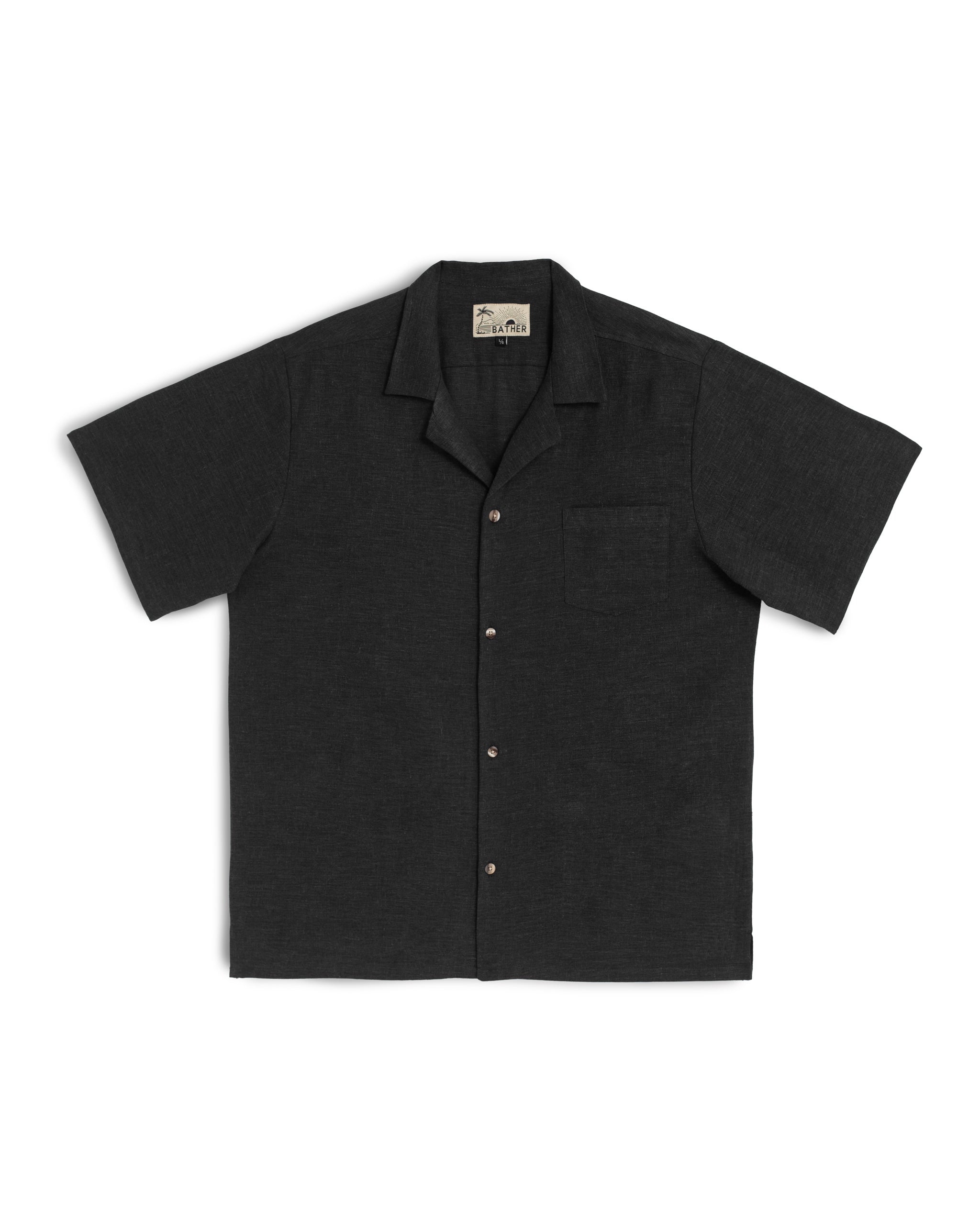 Front view of the Bather Men's Black Linen Camp Shirt, featuring a lightweight 100% black linen fabric with a natural texture, a classic open camp collar, and a single chest pocket against a white background.