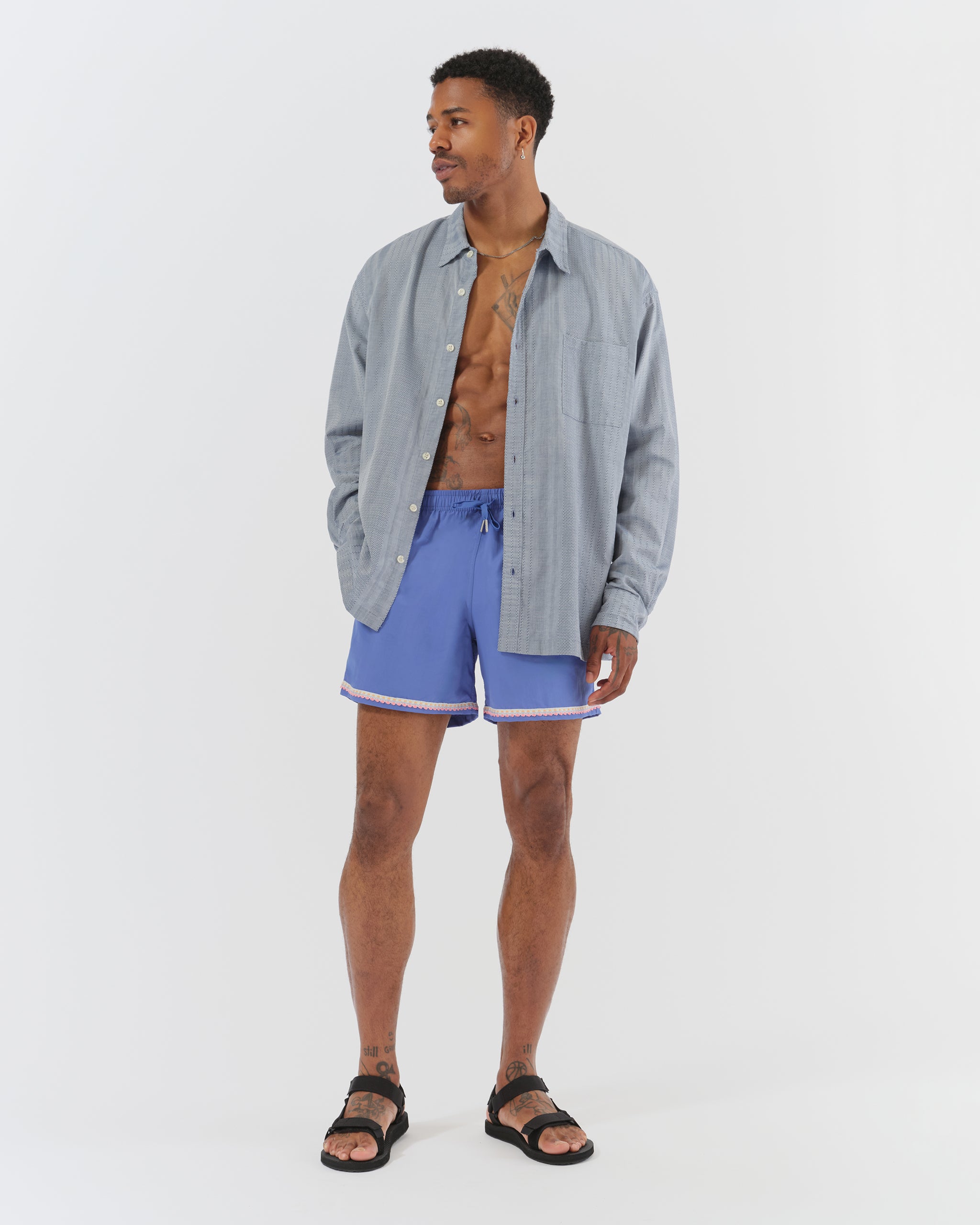 Male model wearing the Bather Men's Cadet Geo Dobby Leisure Shirt with blue shorts for a relaxed, monochromatic summer look.
