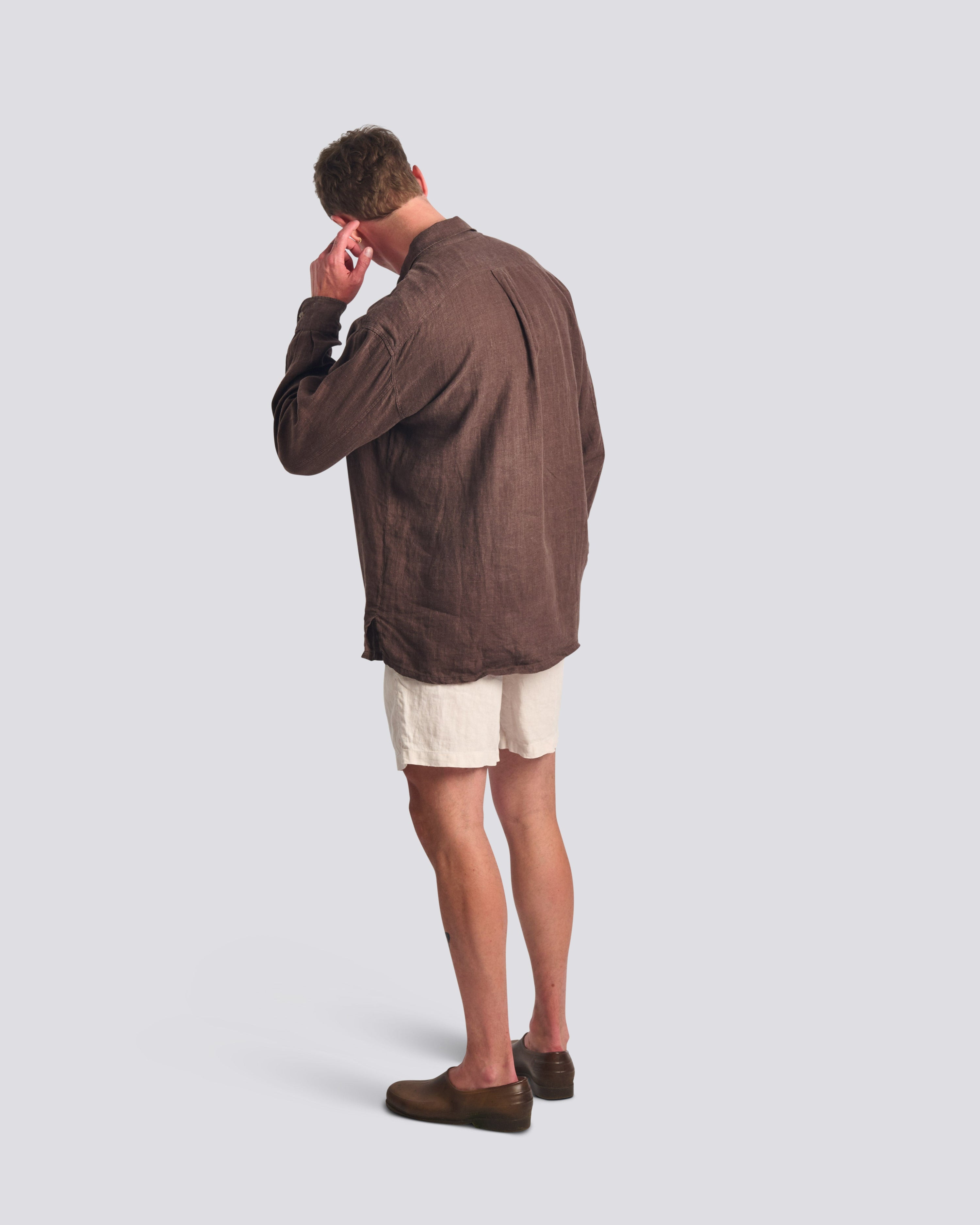 Back of male model wearing the Bather Men's Espresso Linen Leisure Shirt in a relaxed fit, showcasing the lightweight brown linen and white linen leisure shorts for a sophisticated summer look 