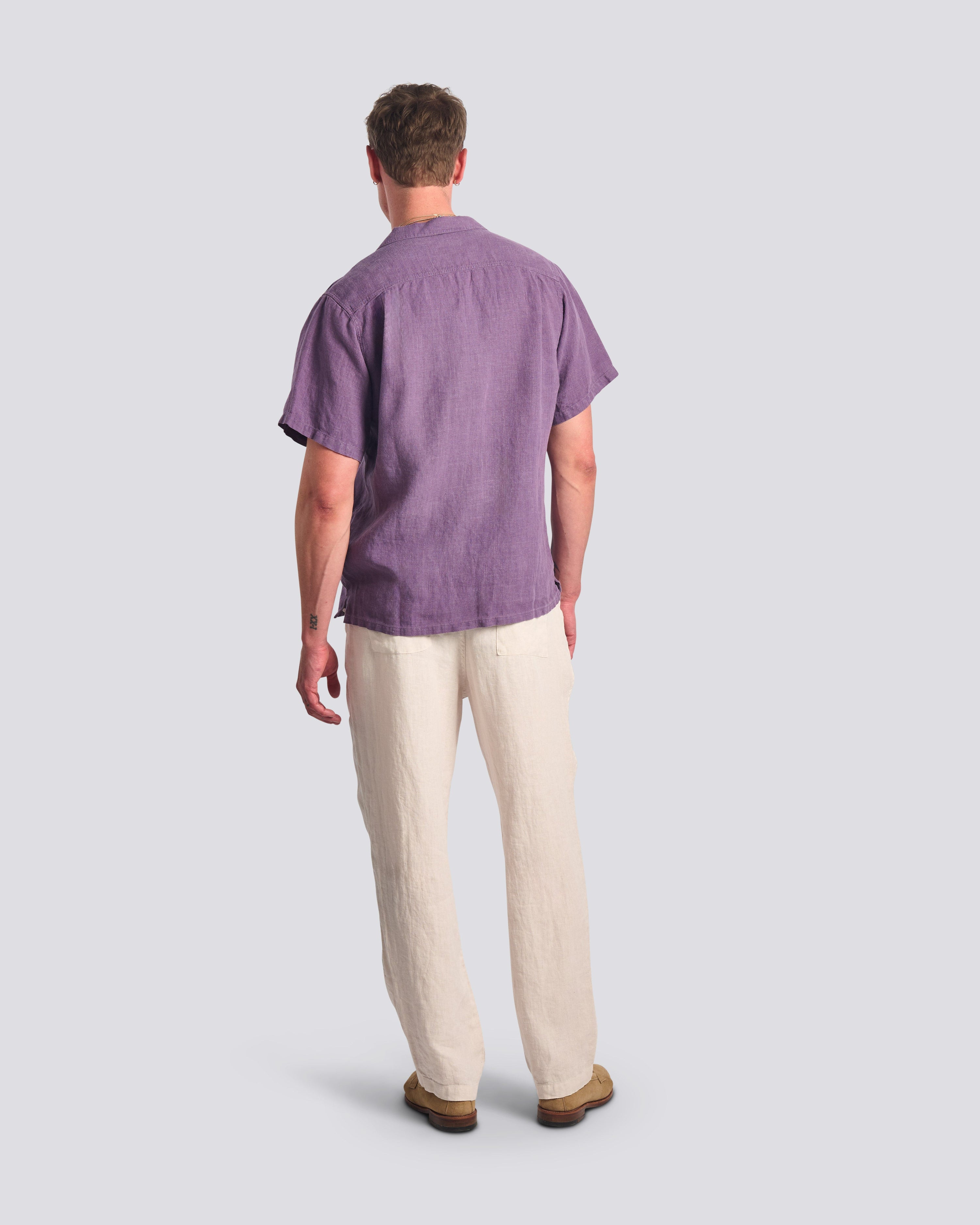 Bather Men's Grape Linen Camp Shirt in muted purple, showing a rear view of the regular fit and textured 100% linen fabric on a model.