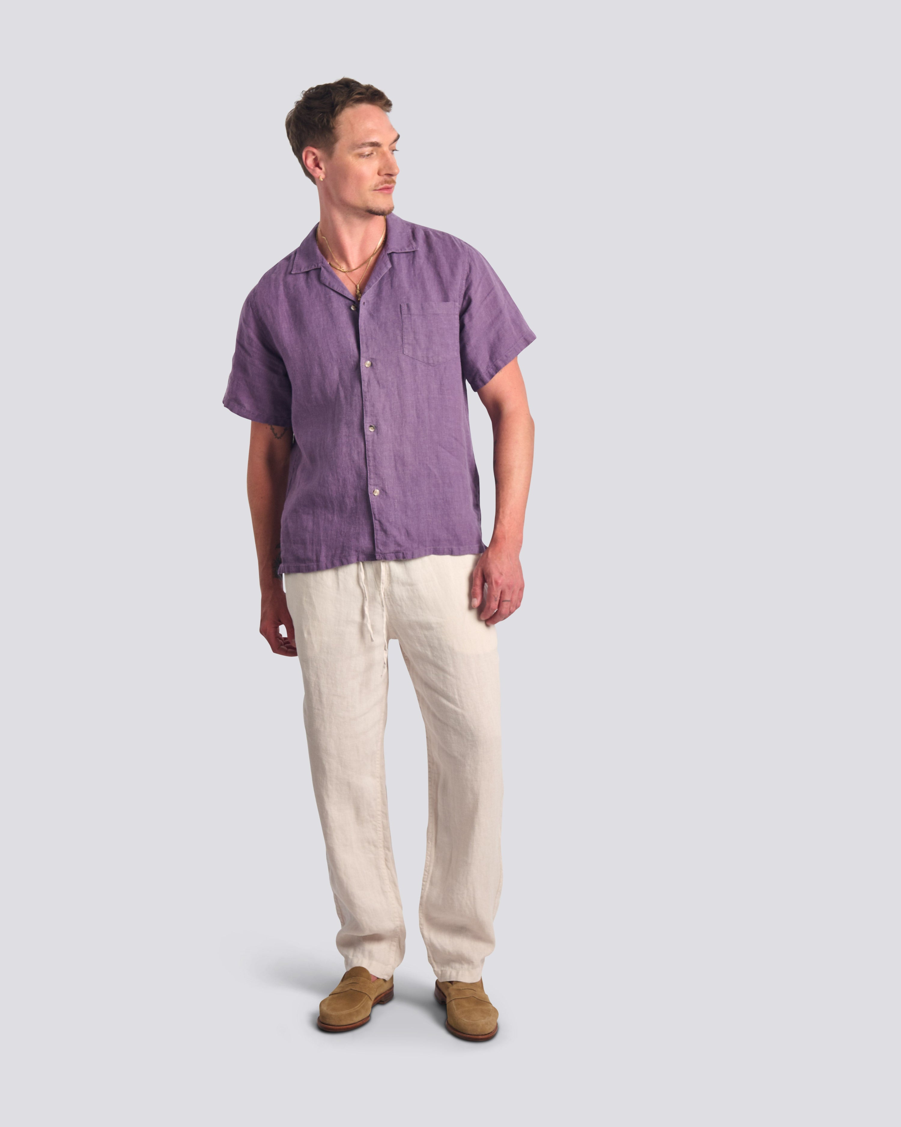 Bather Men's Grape Linen Camp Shirt in muted purple, styled with off-white linen trousers and tan suede shoes on a model.