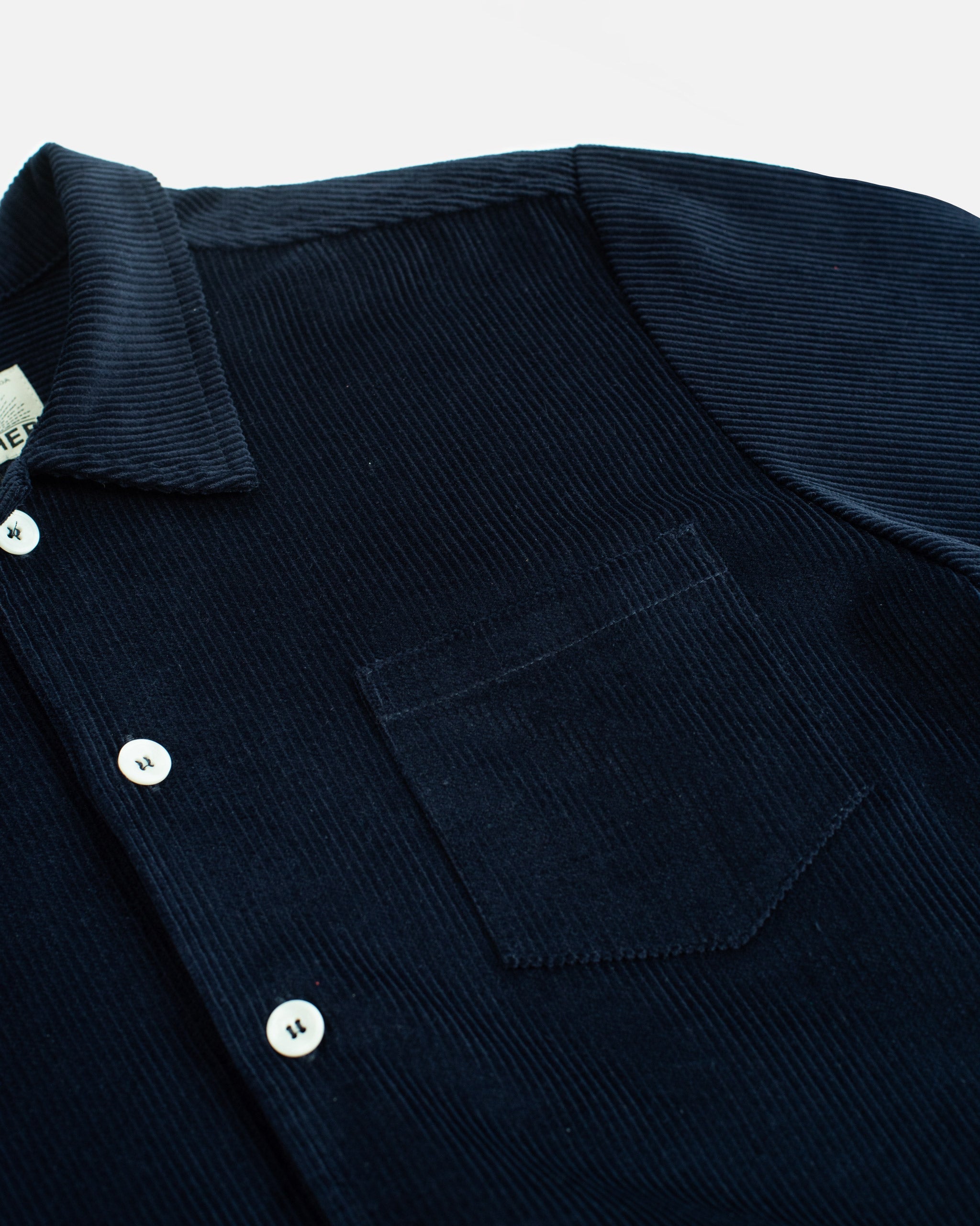 Close-up of the Bather Men's Oxford Corduroy Leisure Shirt in navy blue, showing the ribbed 8-wale corduroy texture, a chest pocket, and white buttons.