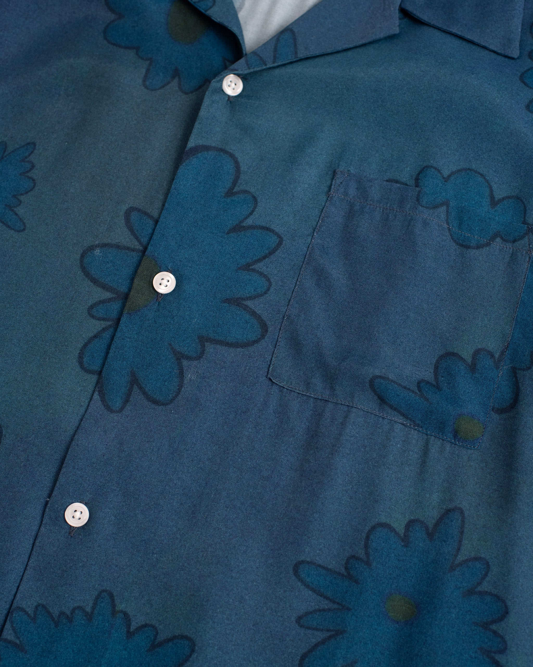 Close-up of the Bather Men's Sapphire Bloomscape Long Sleeve Camp Shirt, highlighting the dark blue and white floral print on lightweight rayon fabric and a clear button detail.