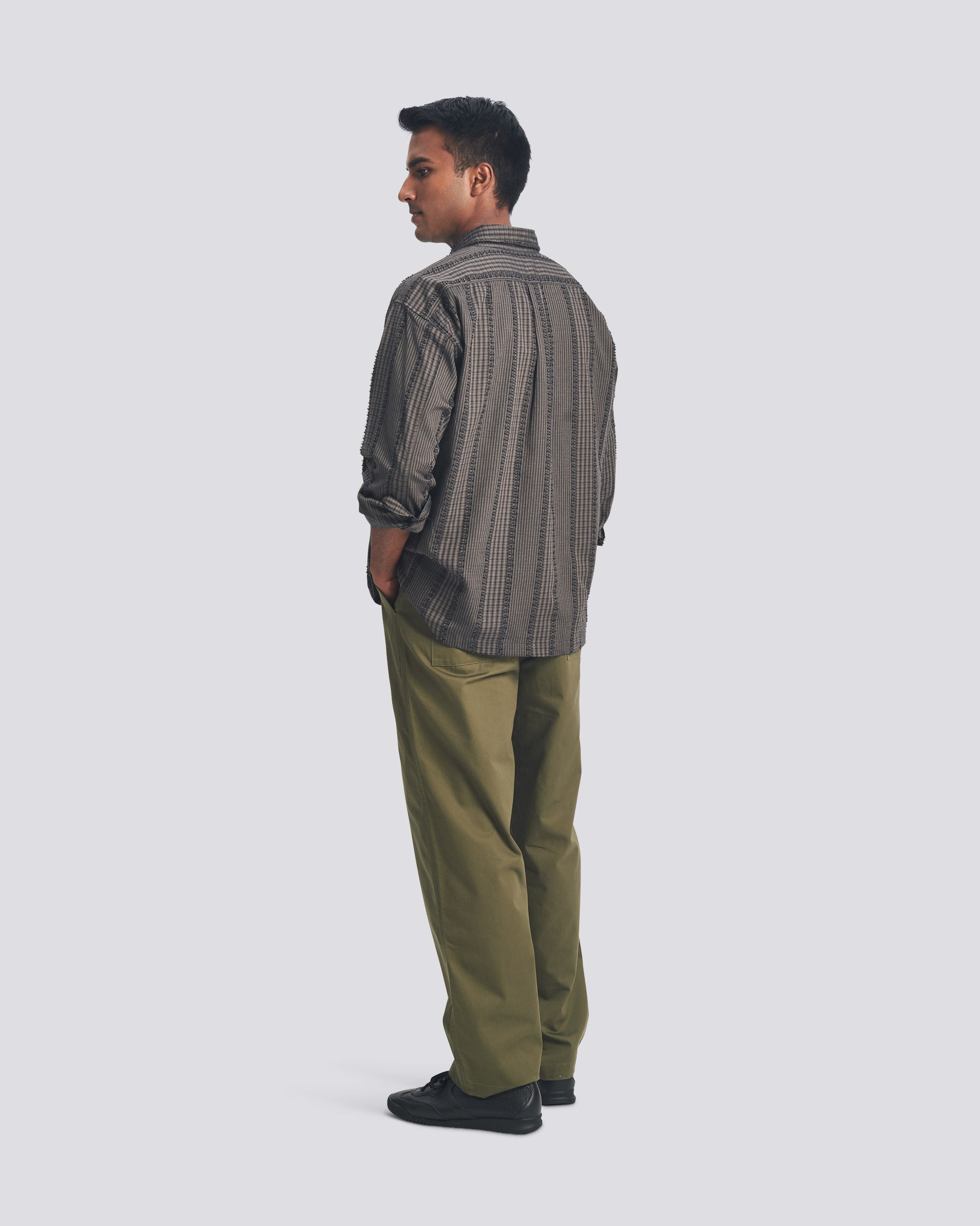 Side-rear view of the Bather Men's Smoke Fringe Leisure Shirt in charcoal grey, showcasing the oversized fit, long sleeves, and the unique texture of the Japanese patchwork fabric.