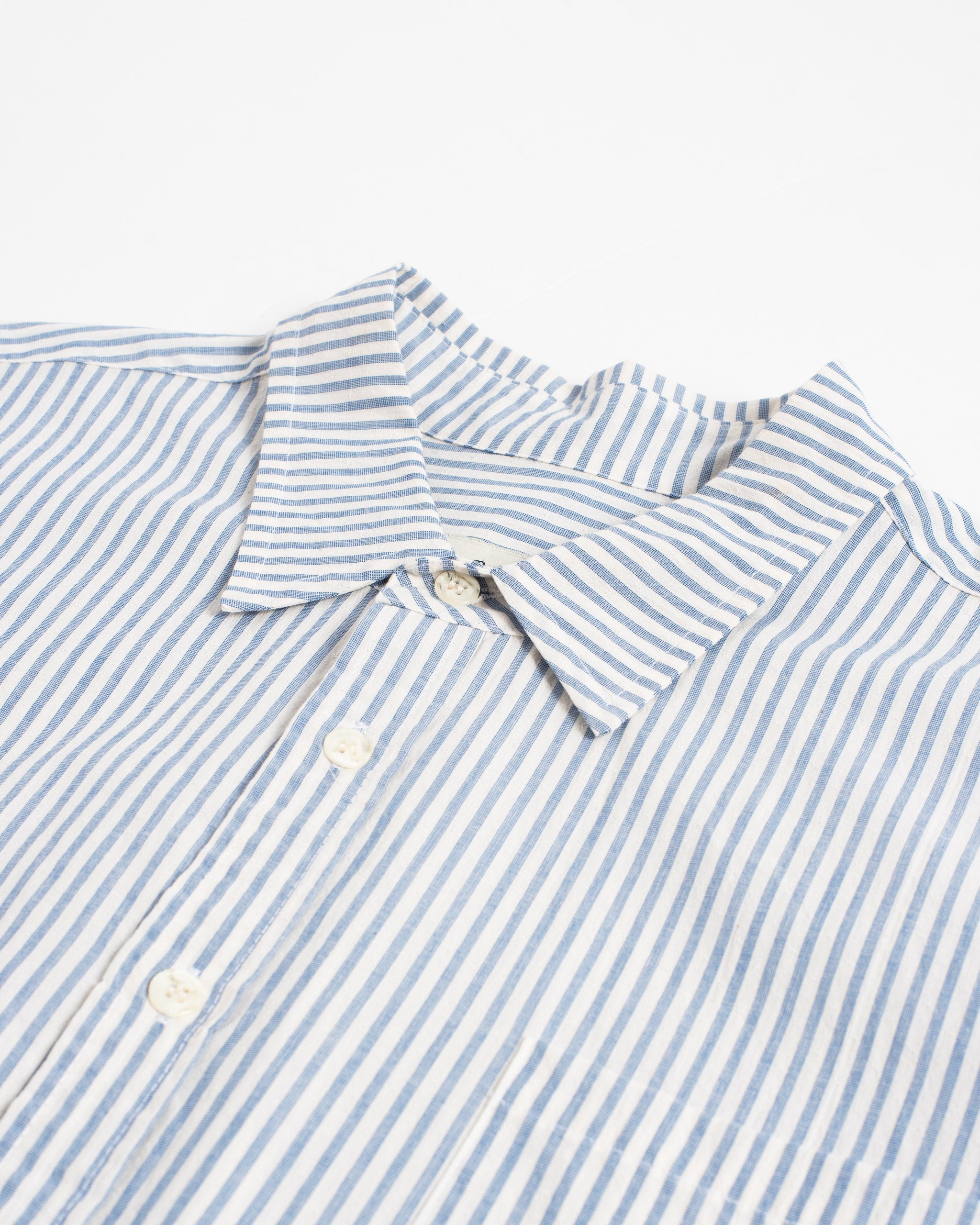 Close-up of white long sleeve collared button up shirt with light blue pinstripe pattern