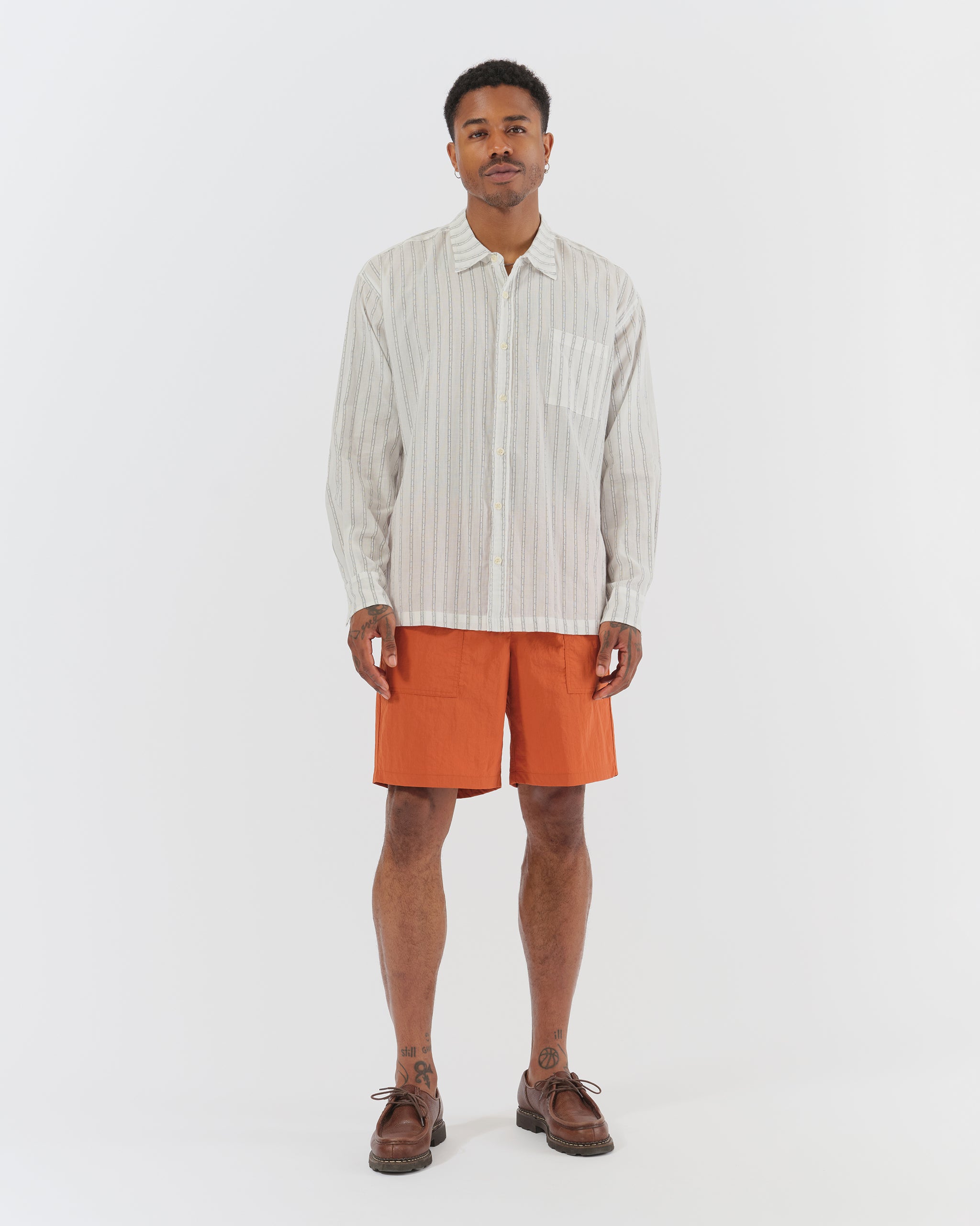 Bather Men’s White Dobby Leisure Shirt with a light blue pinstripe, styled buttoned up with rust-orange swim trunks and dark brown loafers on a model.