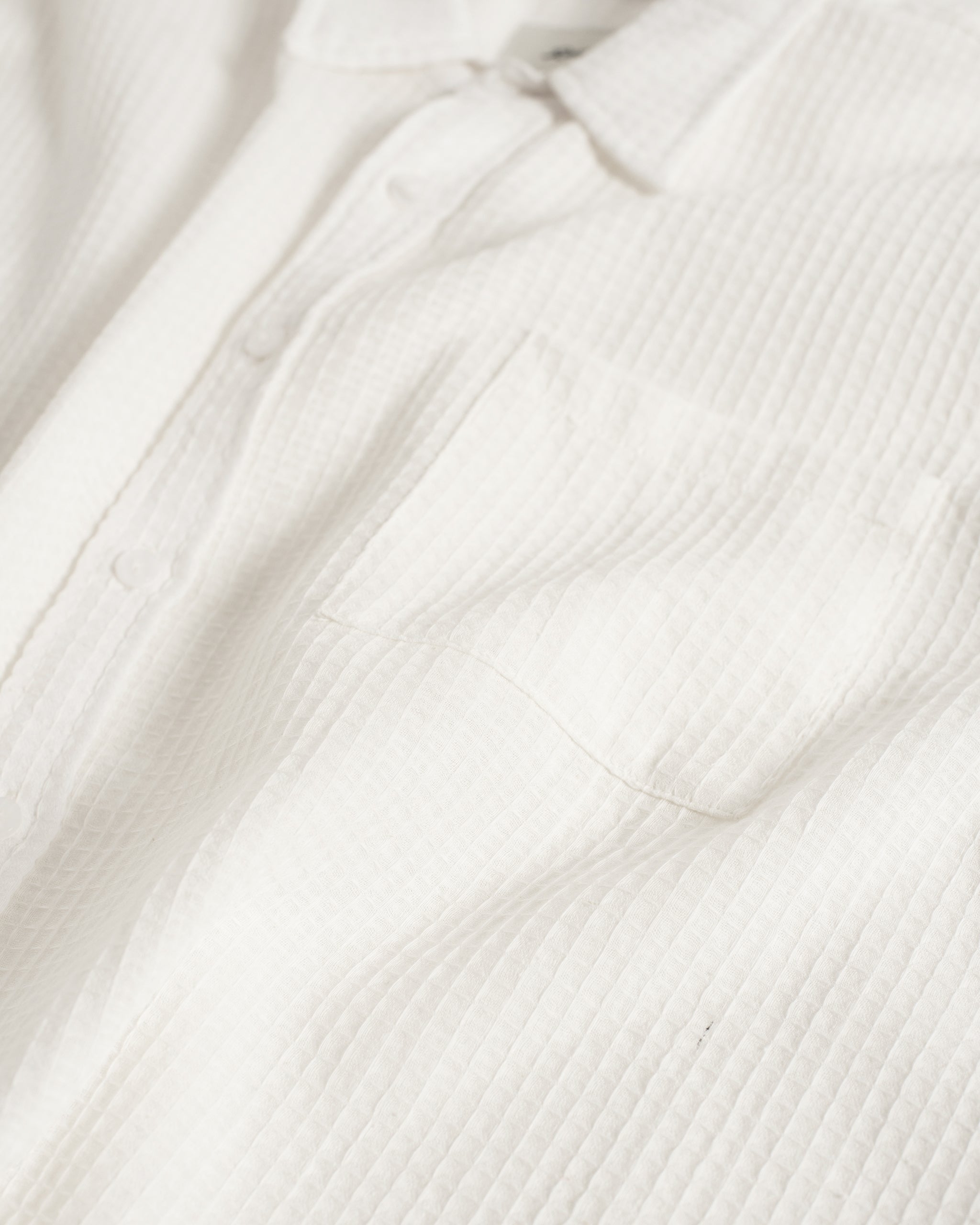 Close-up of the Bather Men's White Waffle Leisure Shirt, highlighting the textured cotton-linen waffle weave fabric, the chest pocket, and the clean white button placket.