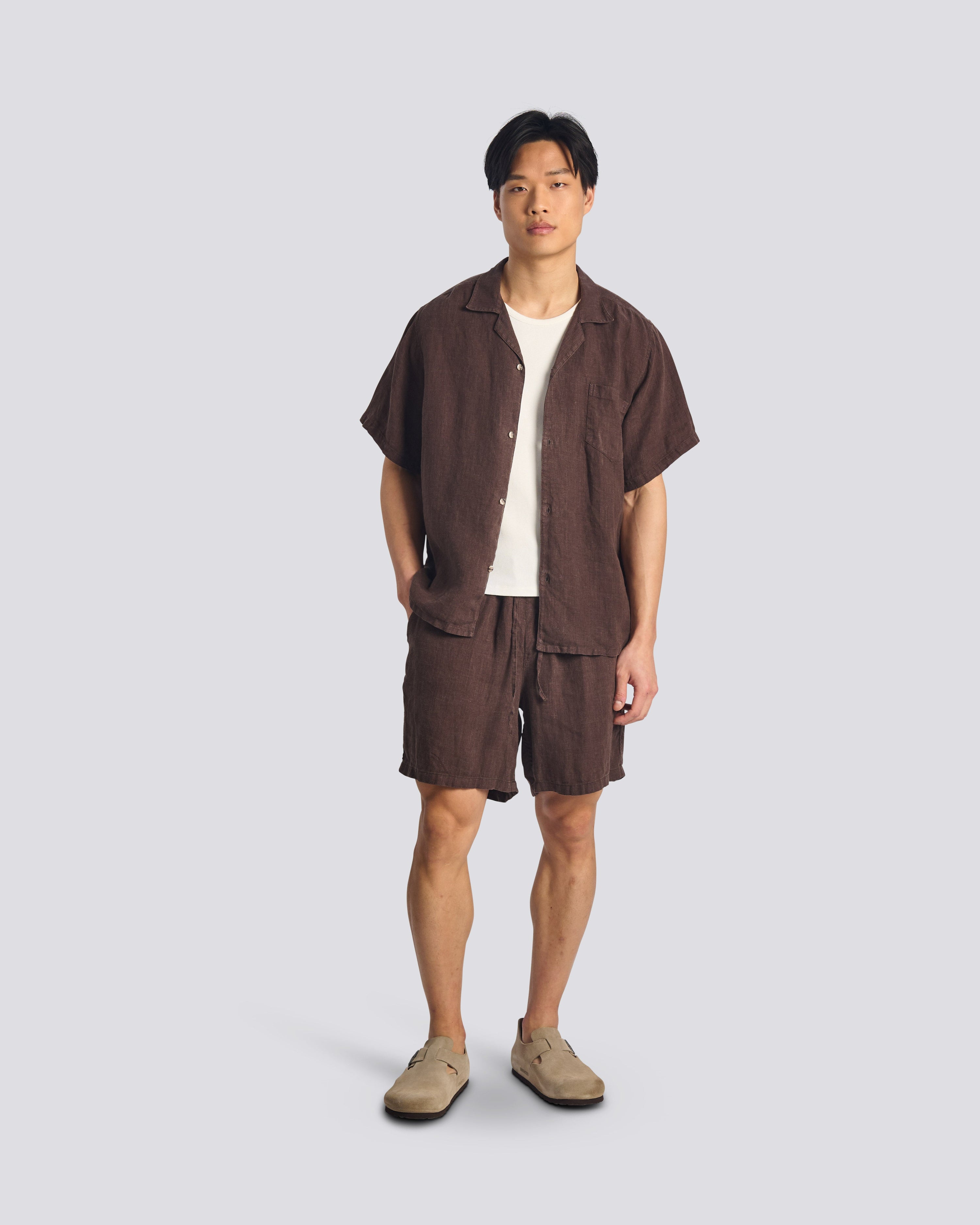 Model wearing Bather men's dark brown linen short with drawstring from the front on a white background