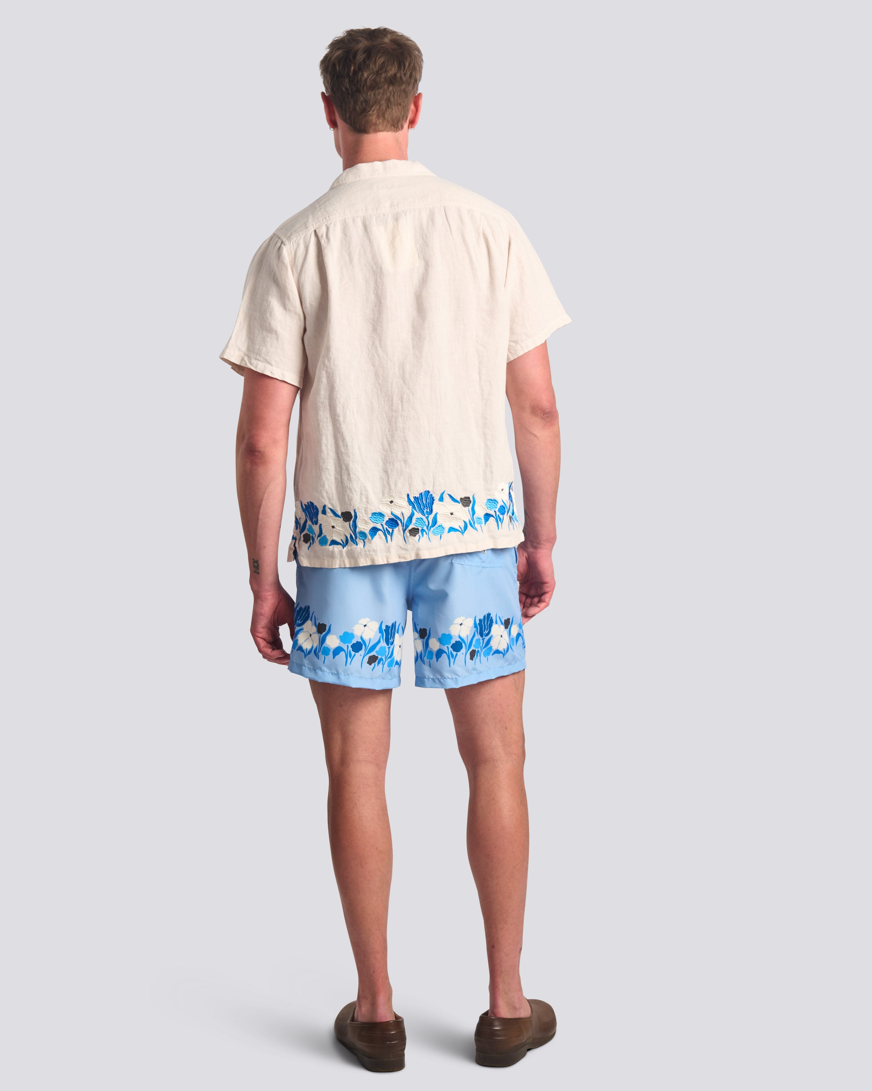 Man wearing Bather light blue floral swim trunks with Bather matching cream camp shirt 