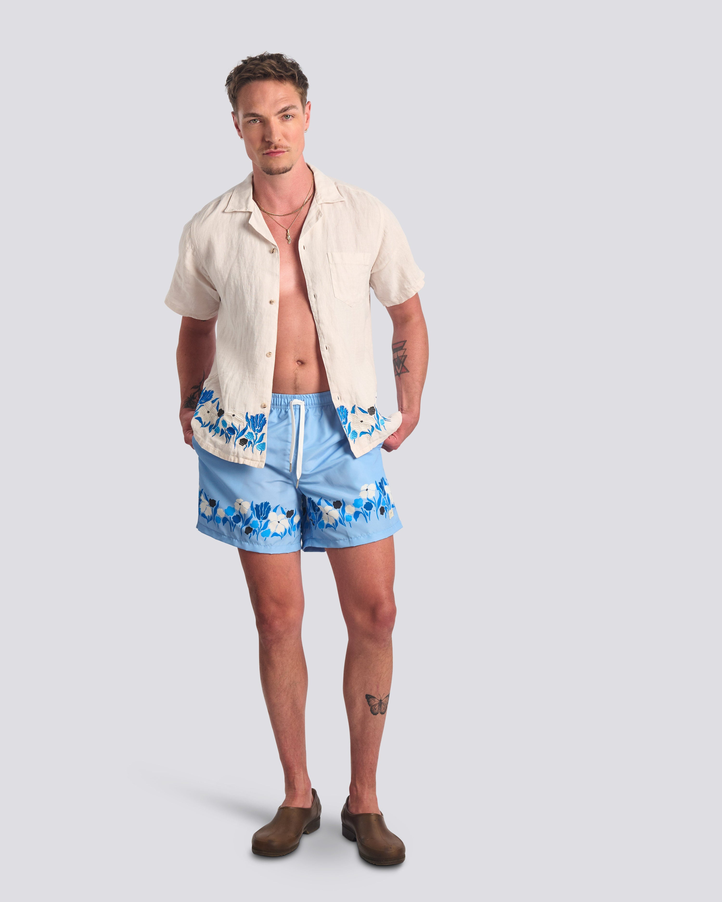 Man wearing Bather light blue floral swim trunks with Bather matching cream camp shirt 