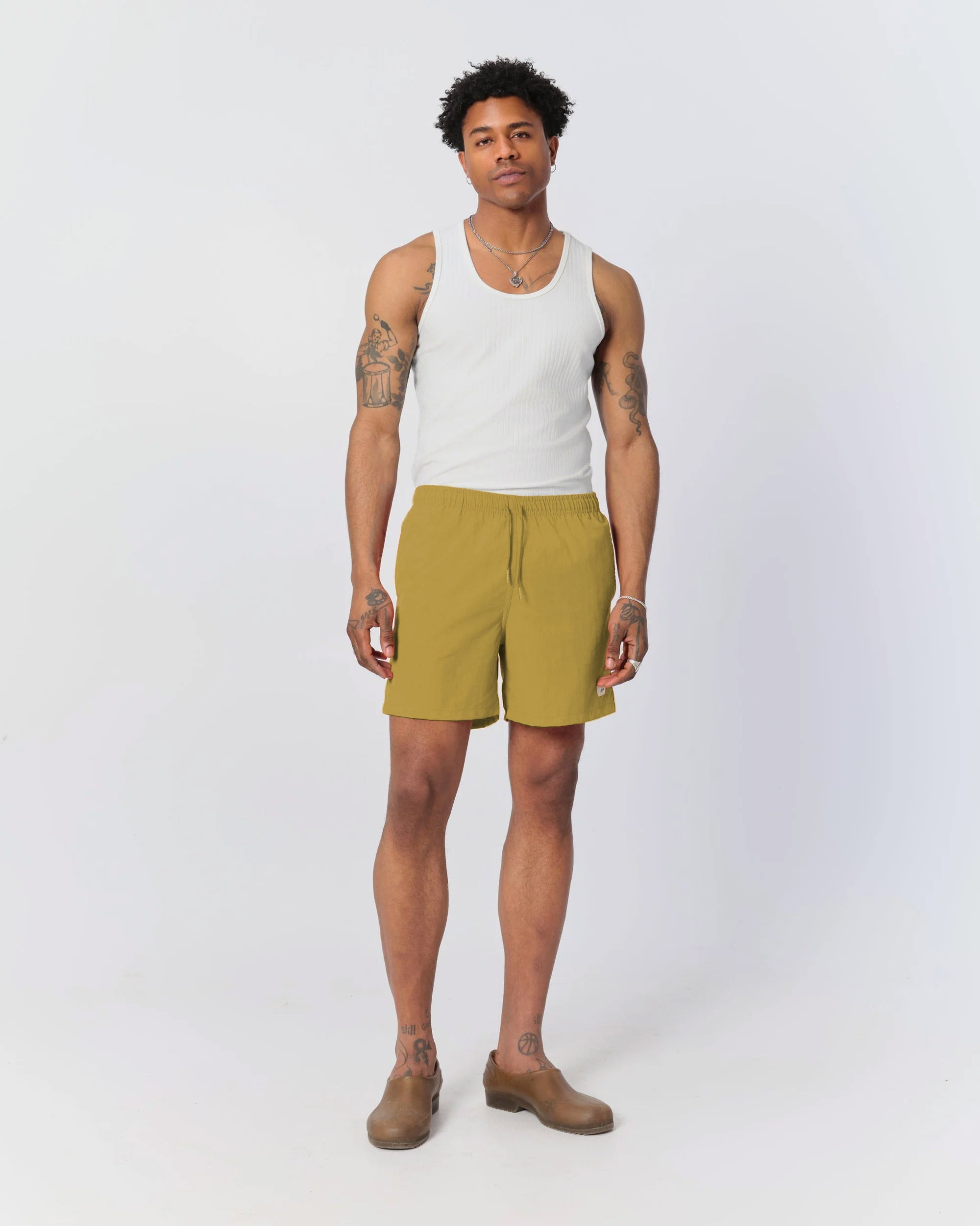 Man wearing Bather mustard yellow swim trunks with Bather white tank top