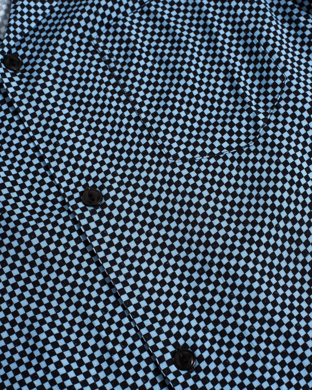 Close-up of a black and light blue checkerboard patterned shirt with dark buttons.