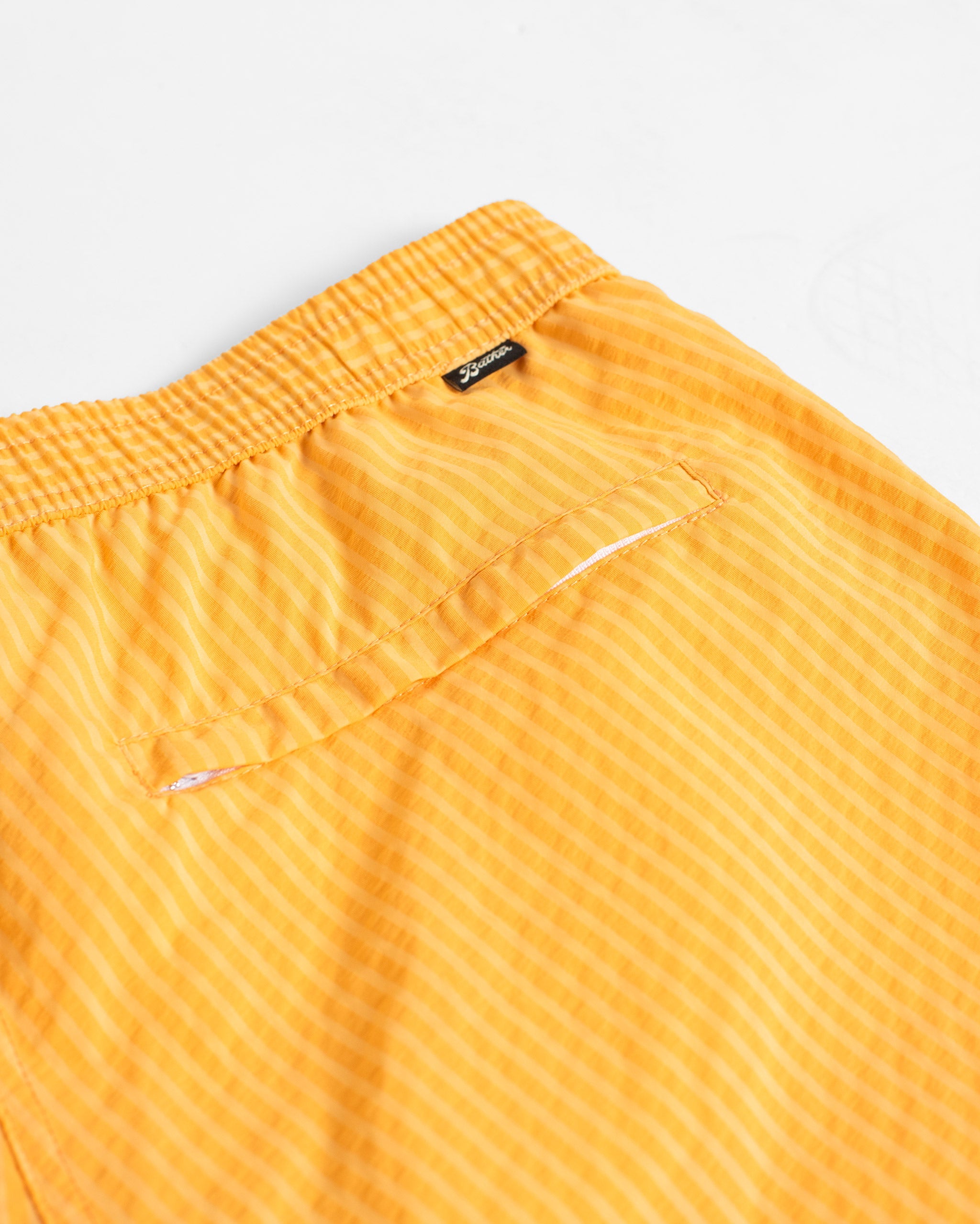 Close-up of yellow striped shorts with a brand label on a white background