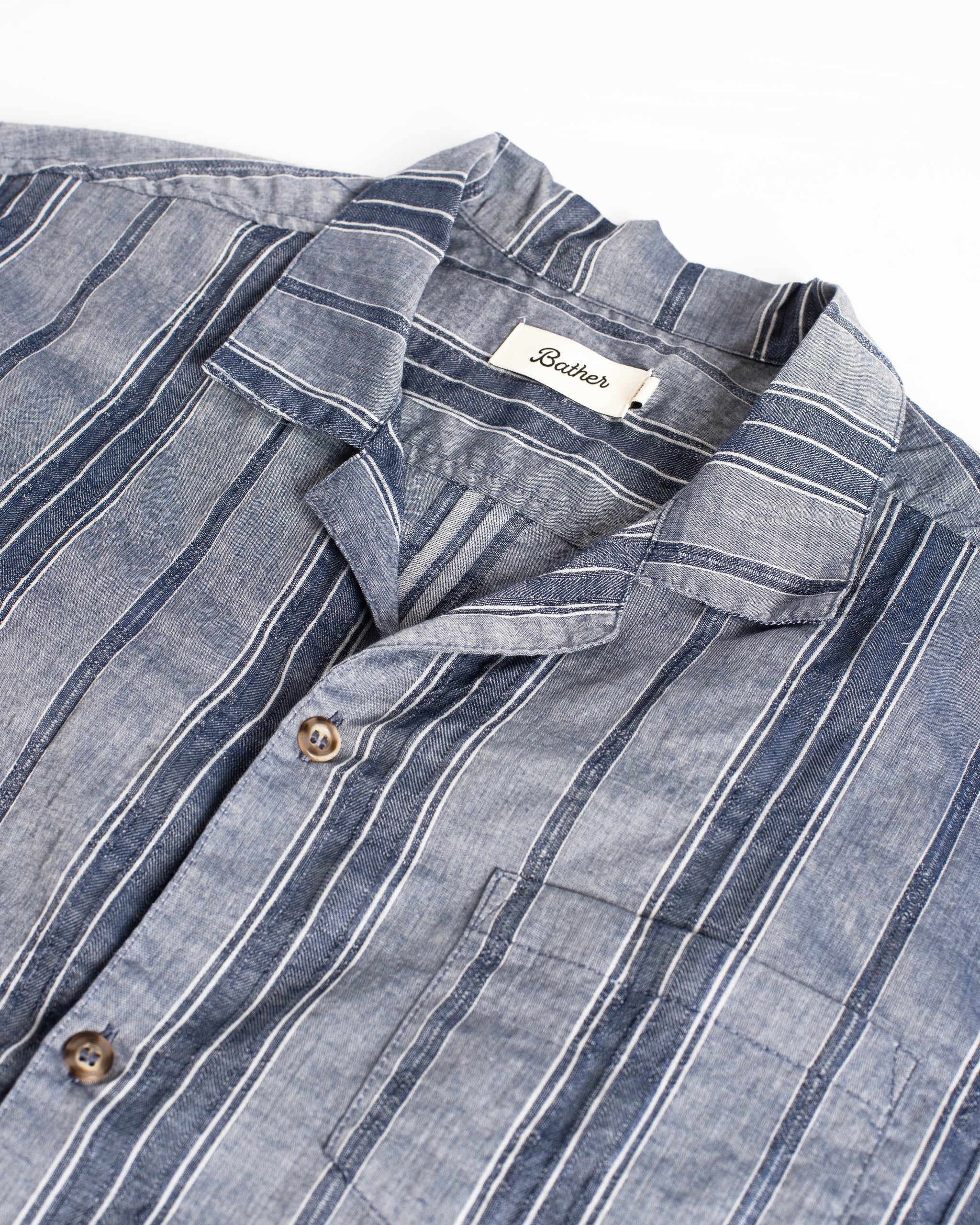 Close-up of a blue striped shirt with a brand label on a white background