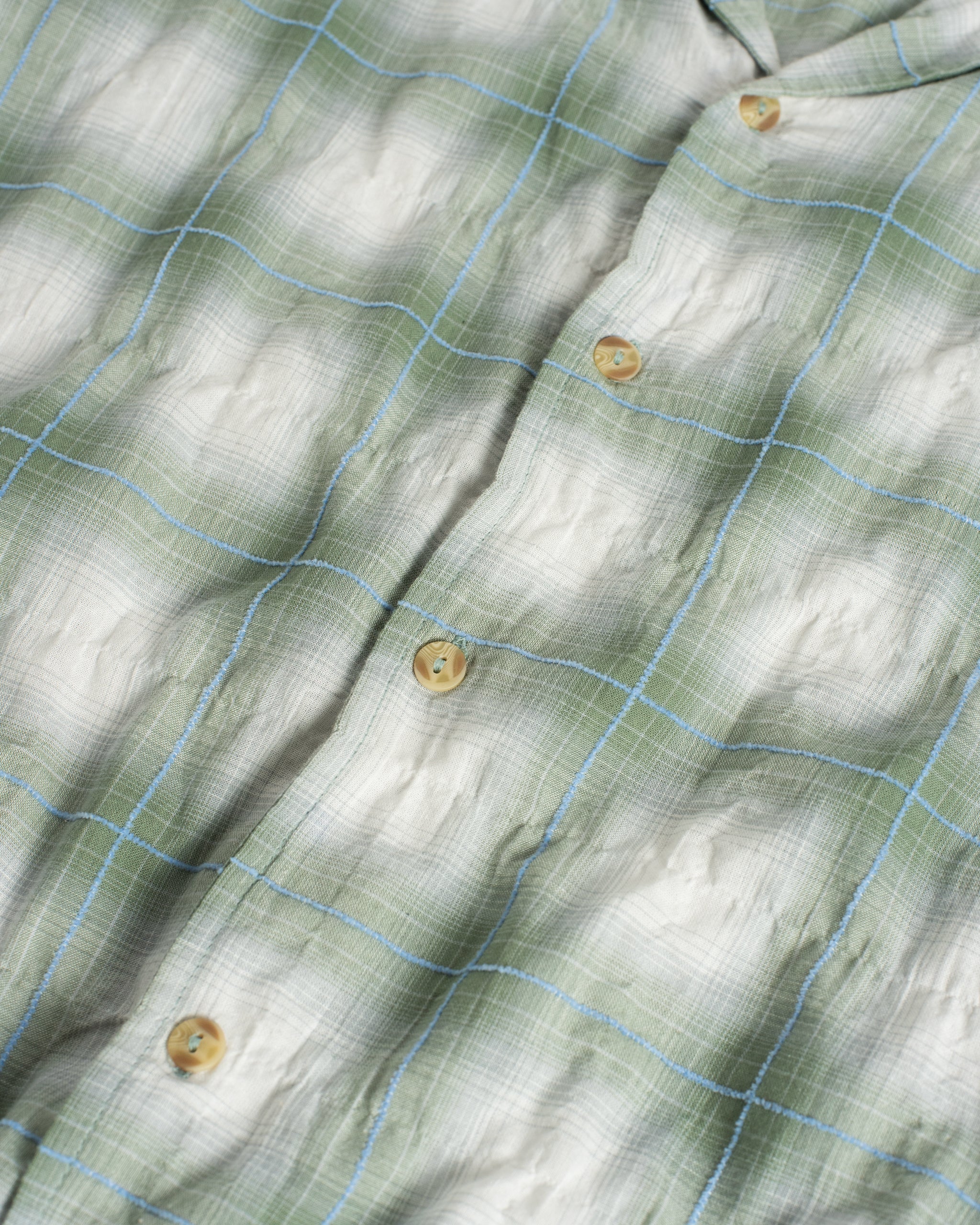 Close-up of a green and white checkered fabric with buttons.