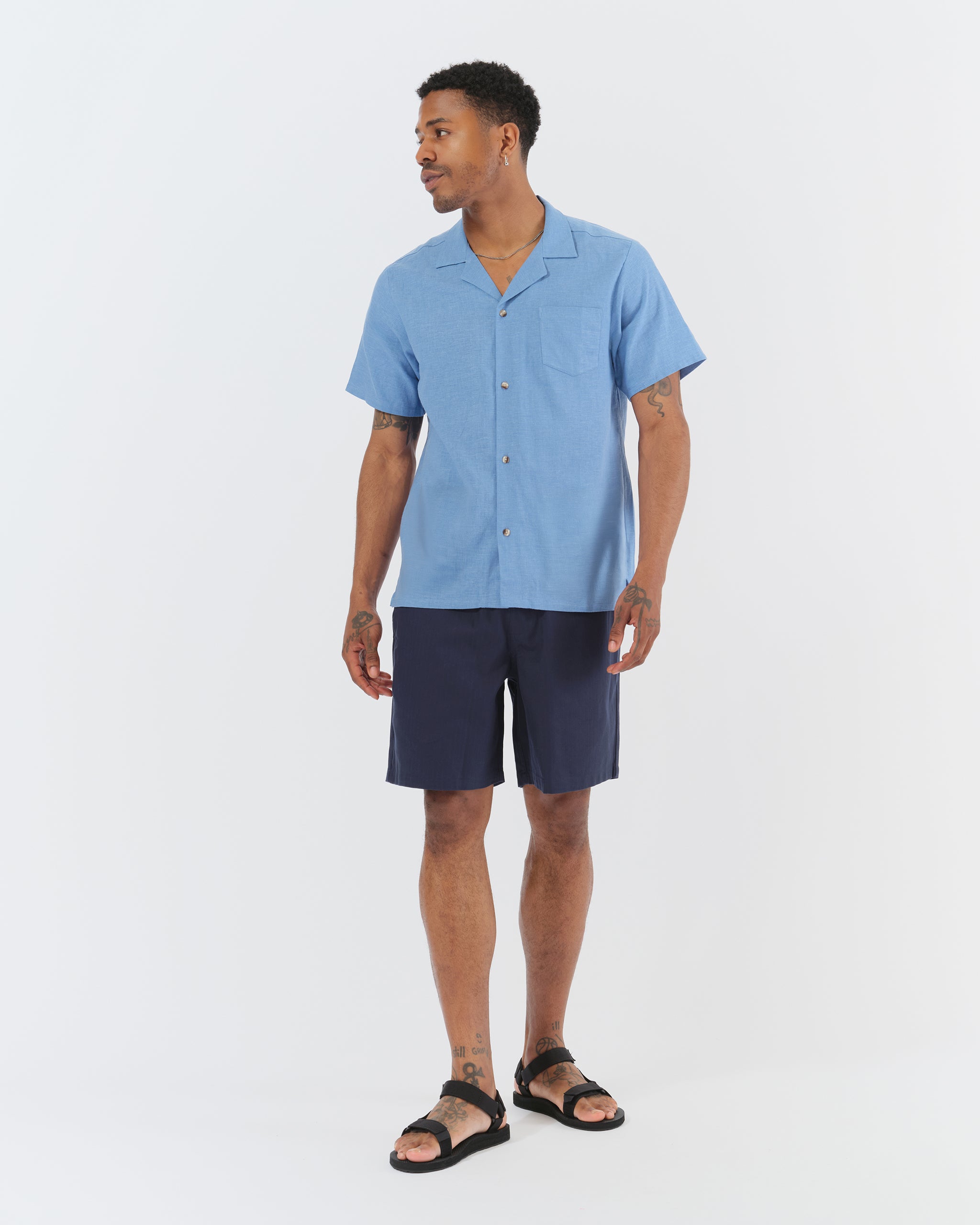 Blue linen camp shirt with a chest pocket and two bottom front pockets on model