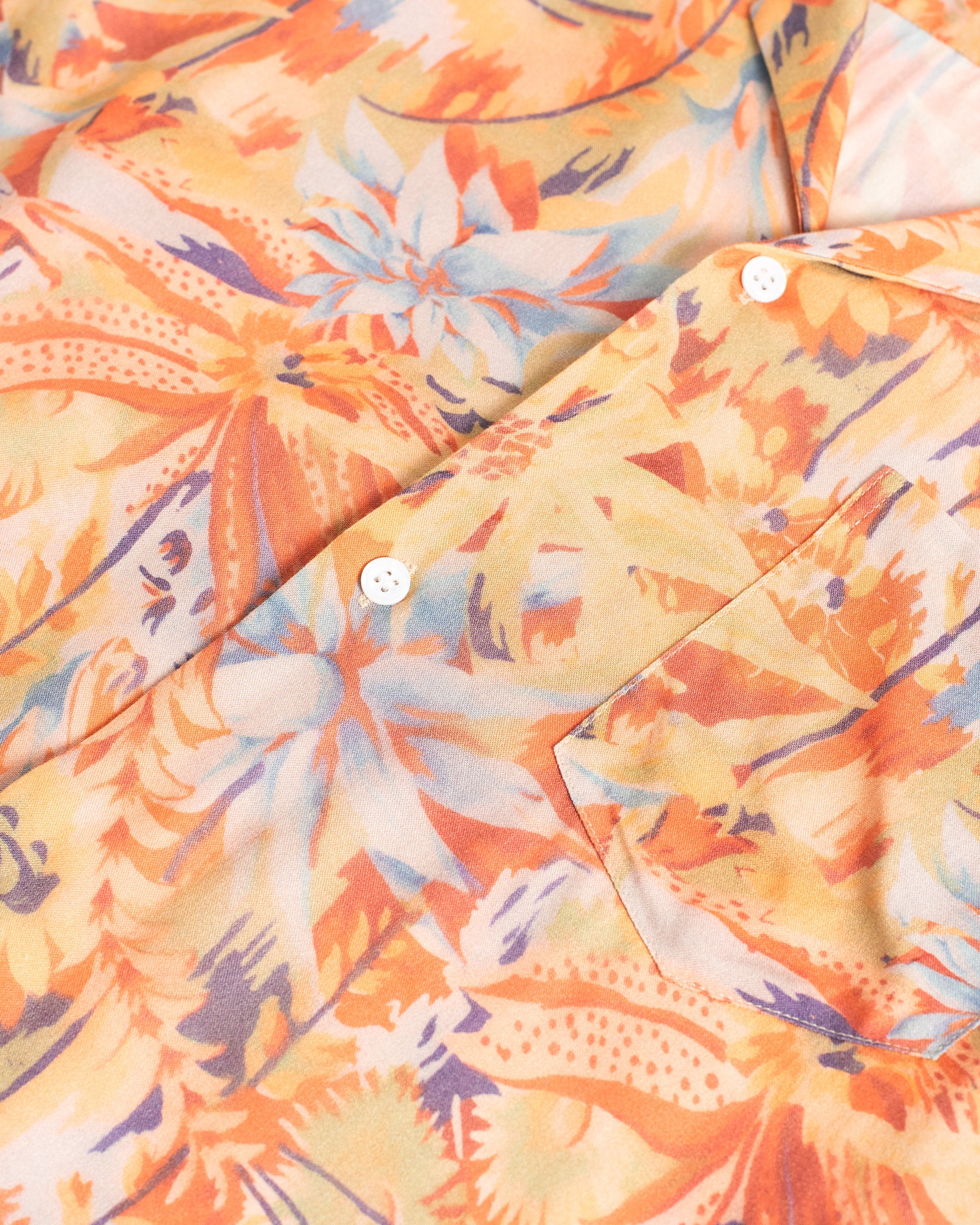 Close-up of a colorful floral patterned shirt with orange, yellow, and blue colors.