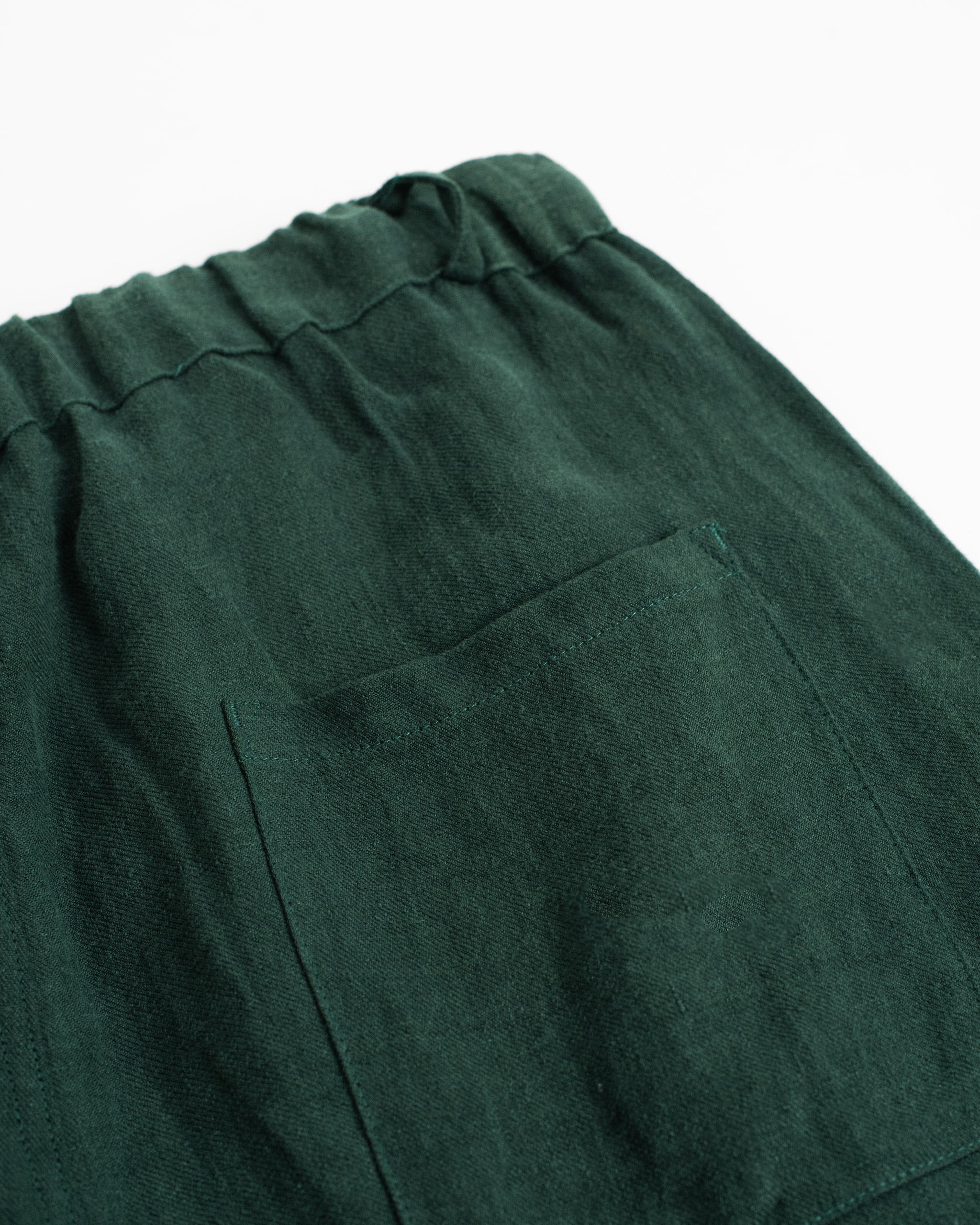 Closeup back pocket detail of Bather men's forest green linen drawstring pants