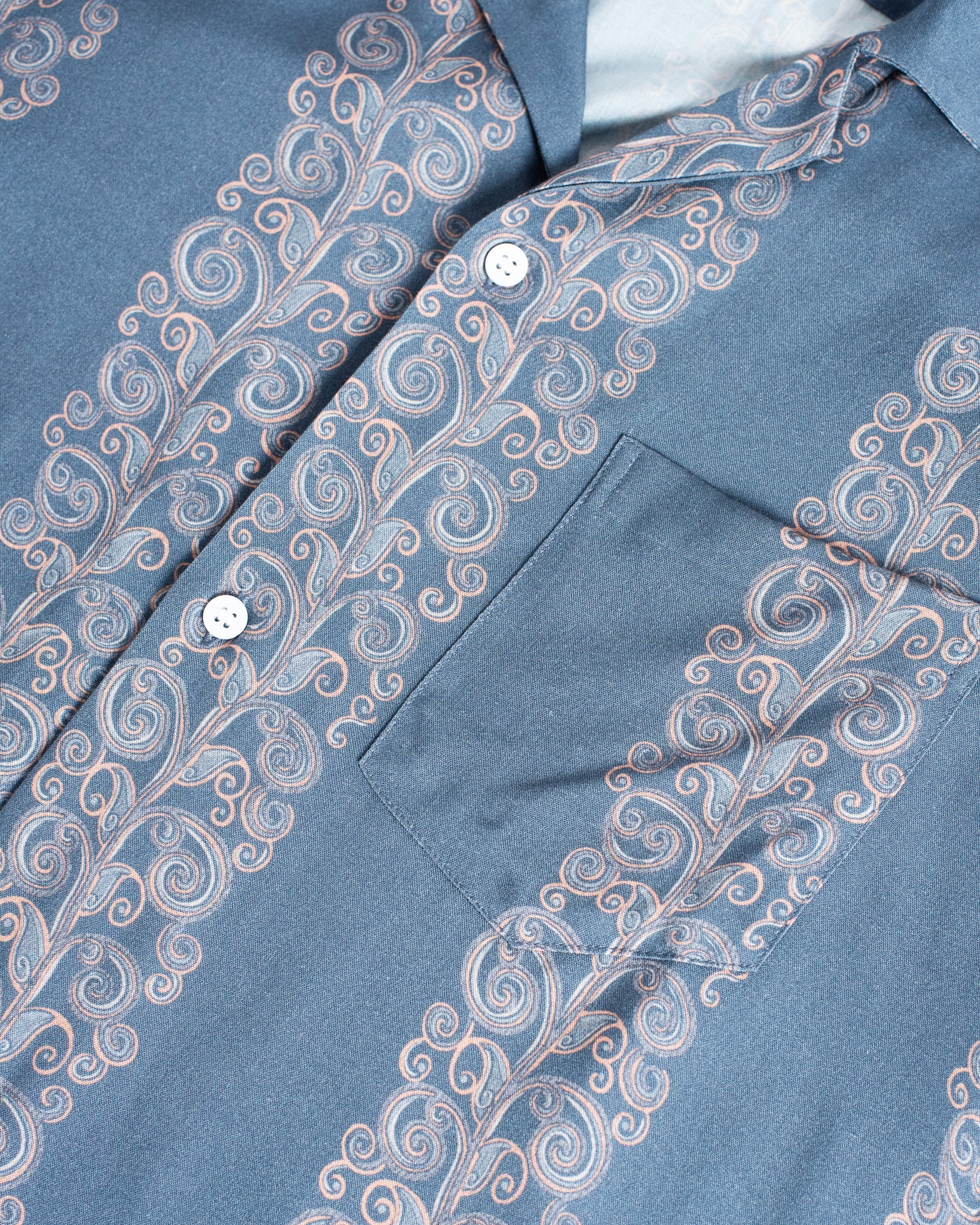 Close-up of a blue shirt with intricate white embroidery