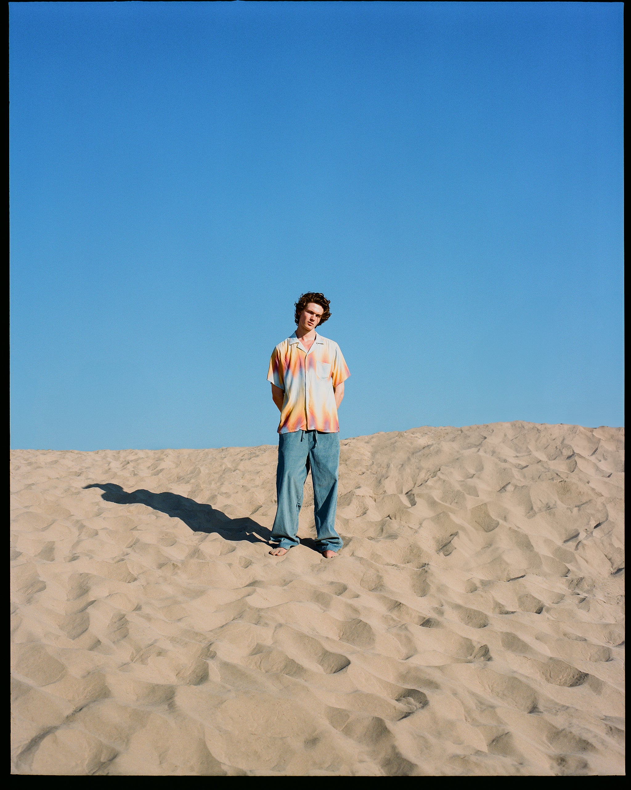 beach shot of man wearing sunset afterglow print shirt
