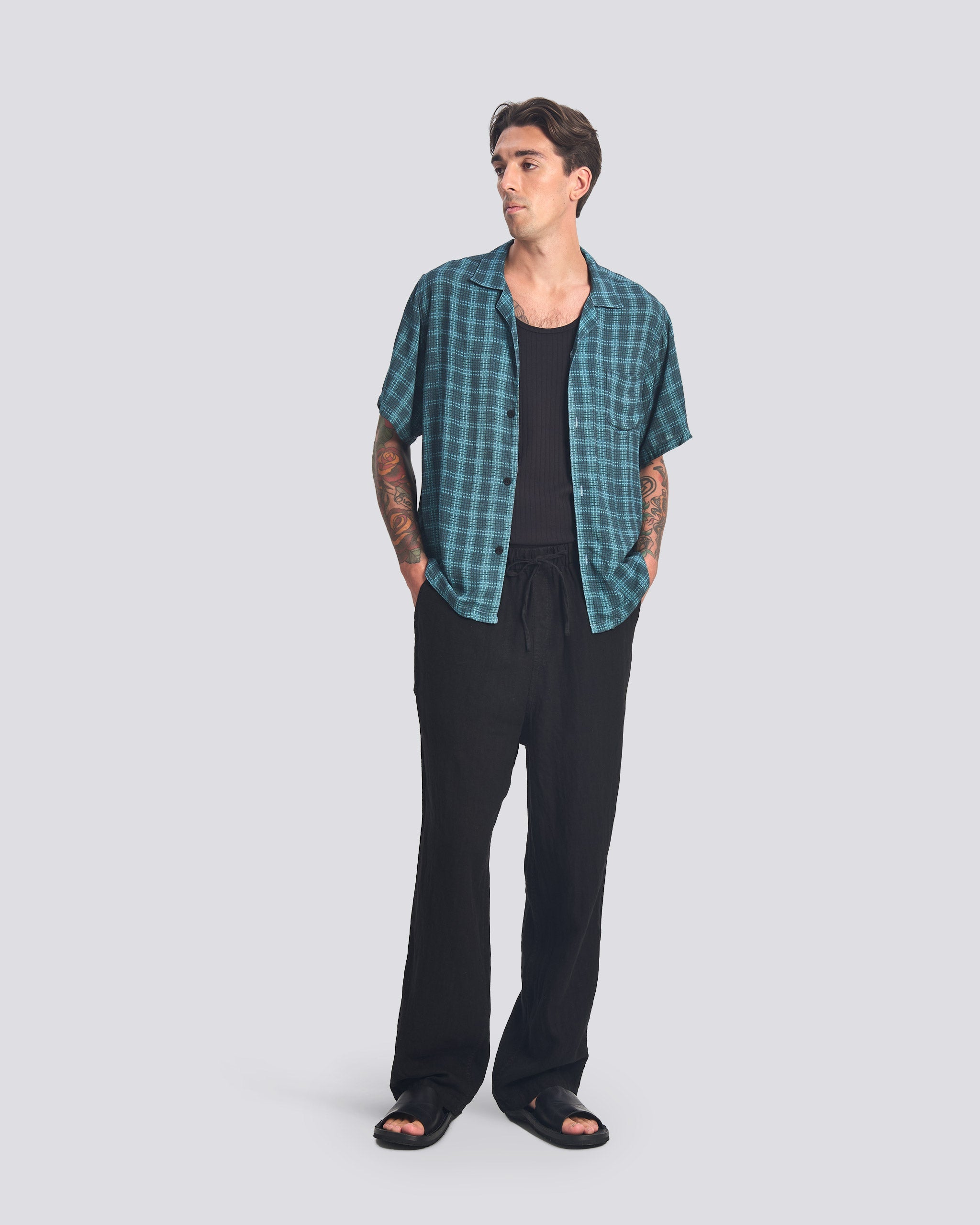man wearing all over print delta tartan shirt with black pants and black shirt