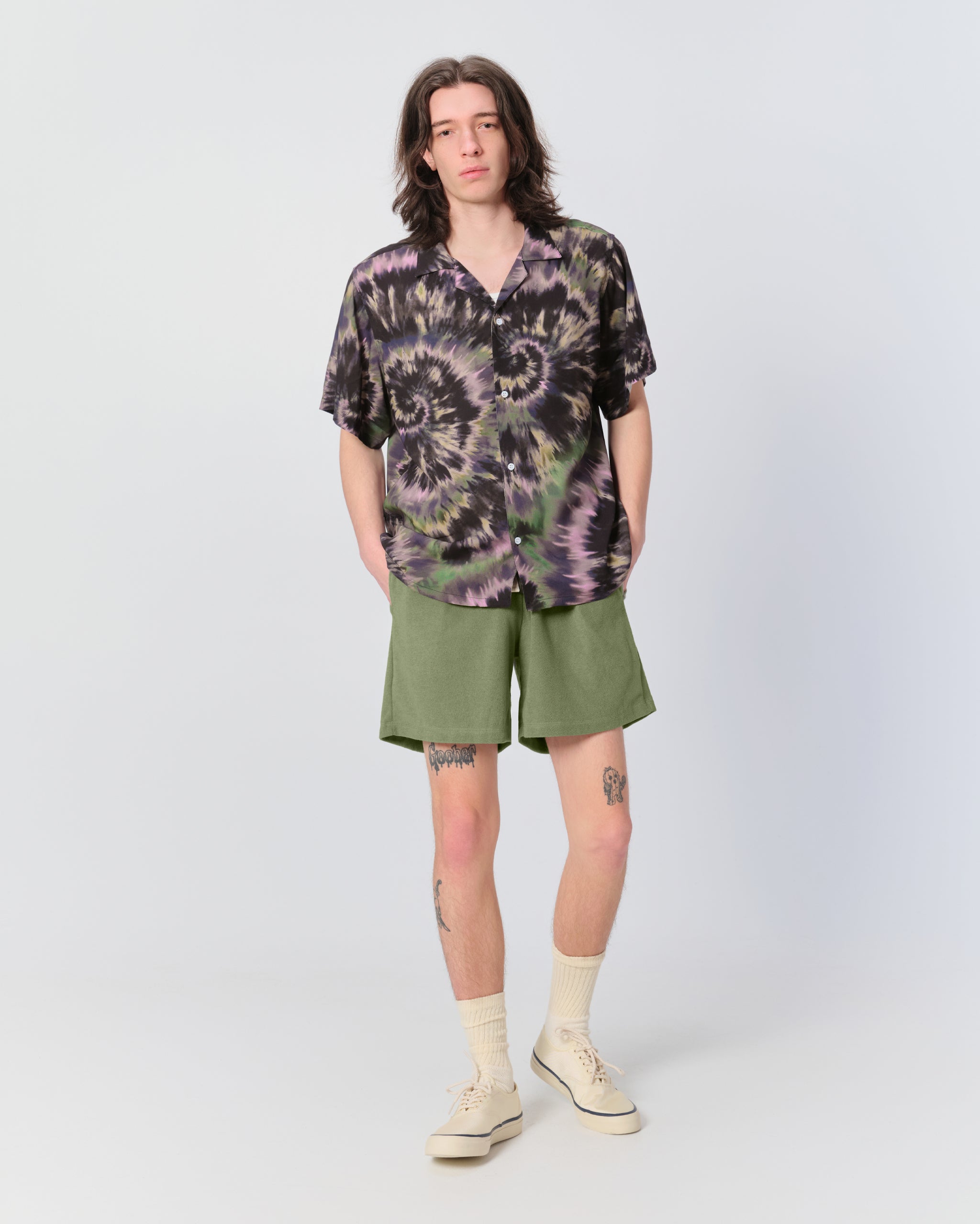 tye dyed shirt button down man wearing shorts with hands in pockets 