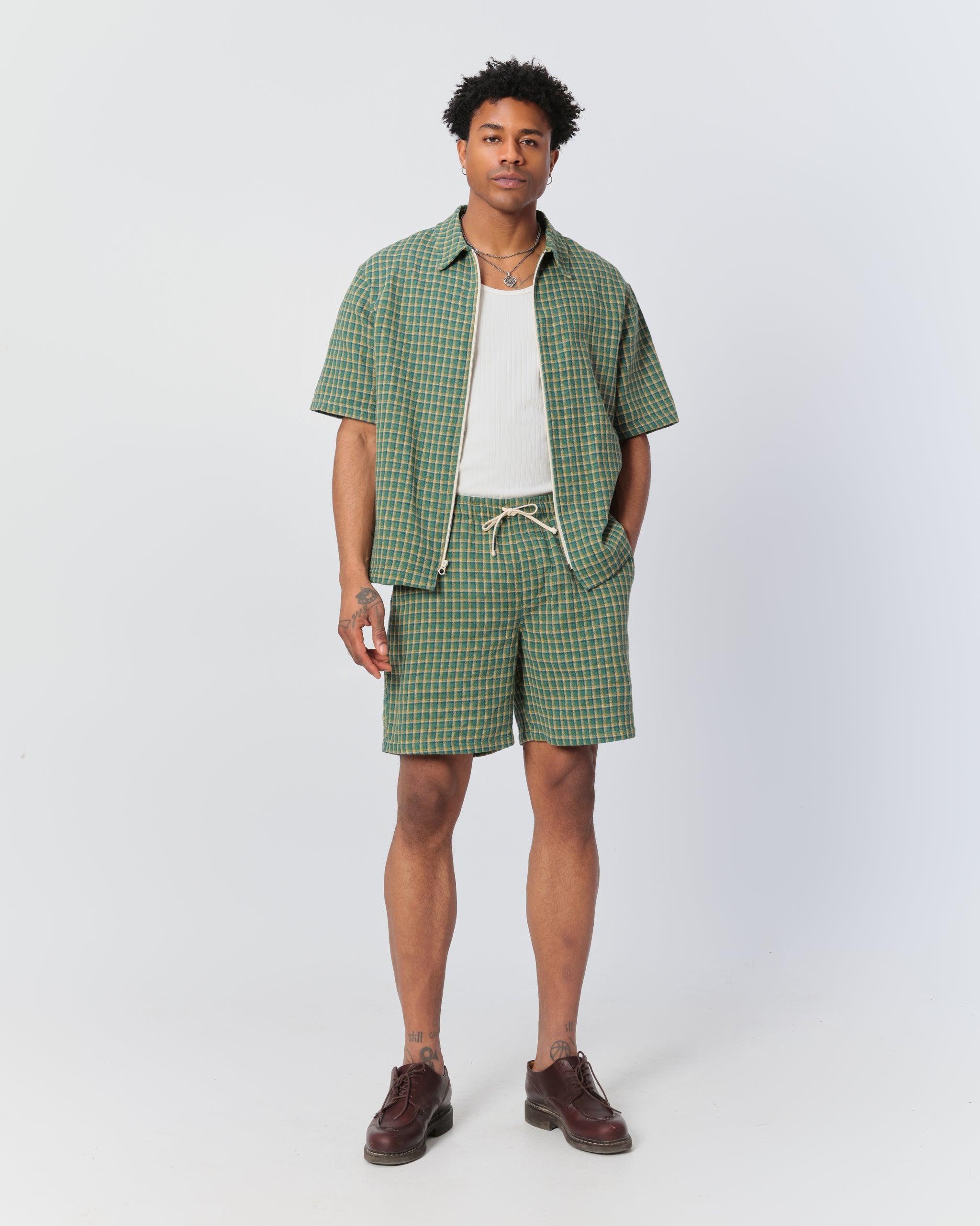 Male model wearing Bather men's green checkered drawstring shorts and matching zip-up shirt